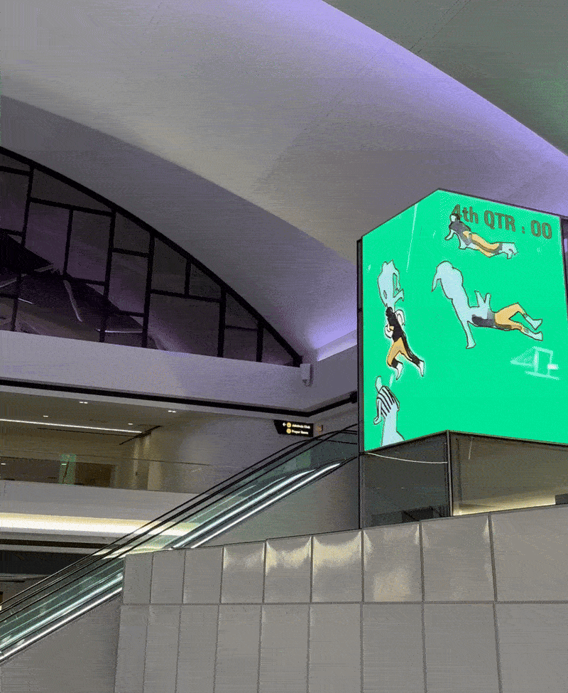 A moving image showing escalators above a hall and video screens showing an artistic rendition of a famous Steelers football game. 