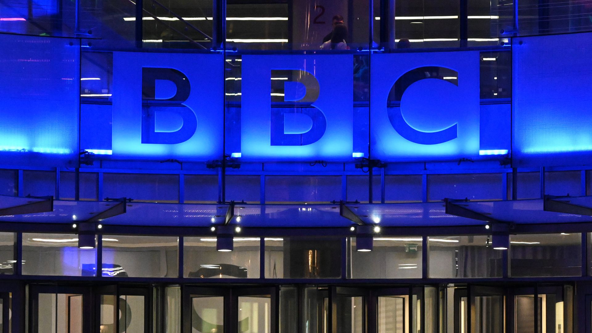 The BBC headquarters in London with its logo lit in blue lighting.