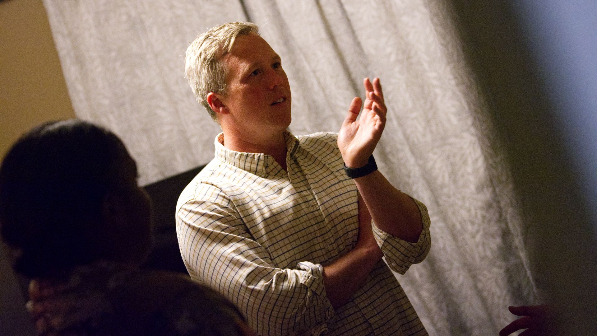 Army Secretary Dan Driscoll, a man, stands inside military barracks and talks with two people barely seen in the photo.
