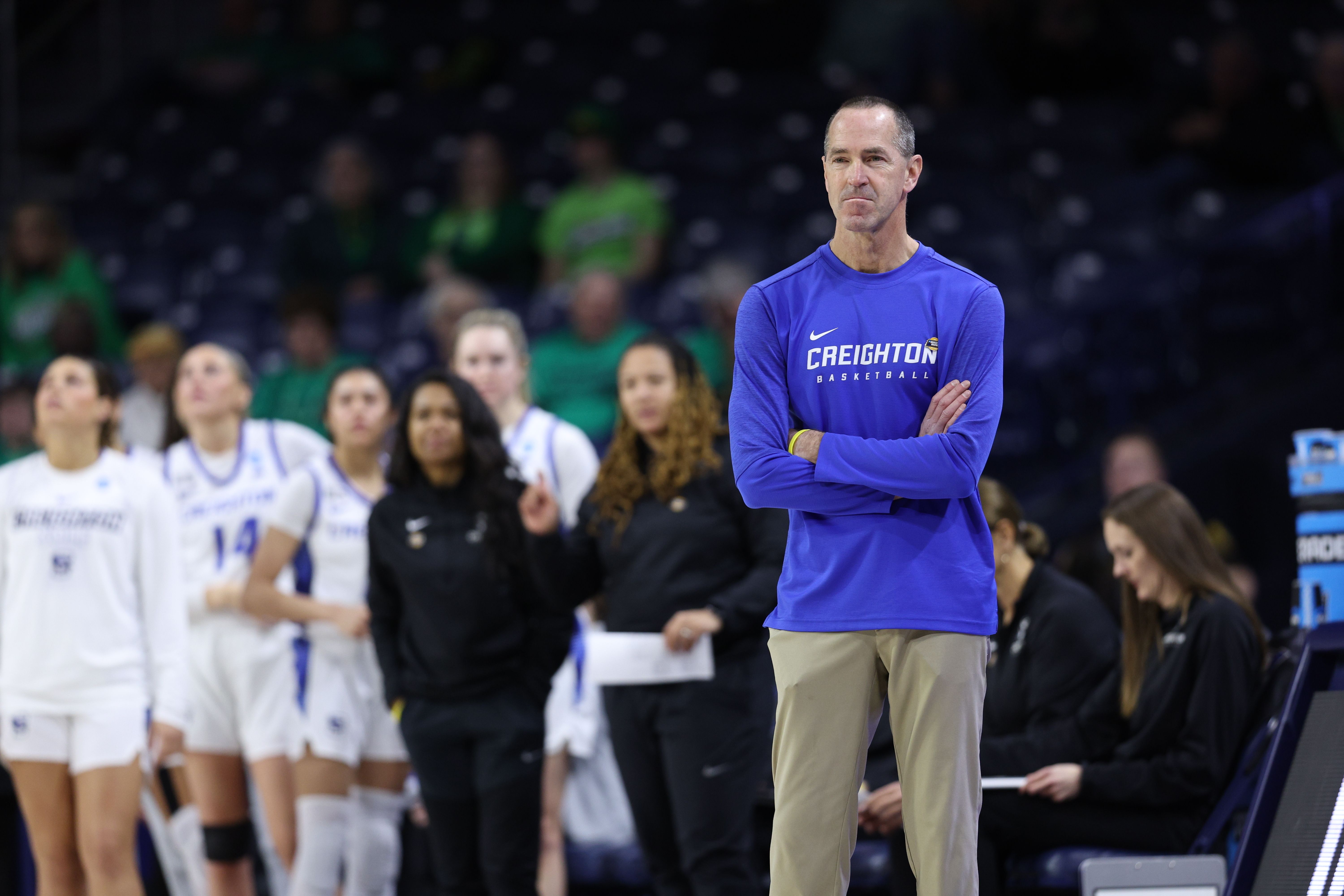 Photo of a coach watching basketball from the side of the court