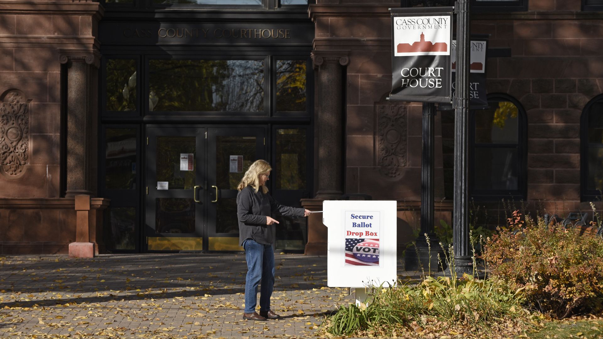 A voter places a ballot for the 2020 Presidential elections in a drop box outside the Cass County Courthouse in Fargo, North Dakota, U.S., on Thursday, Oct. 15, 2020.