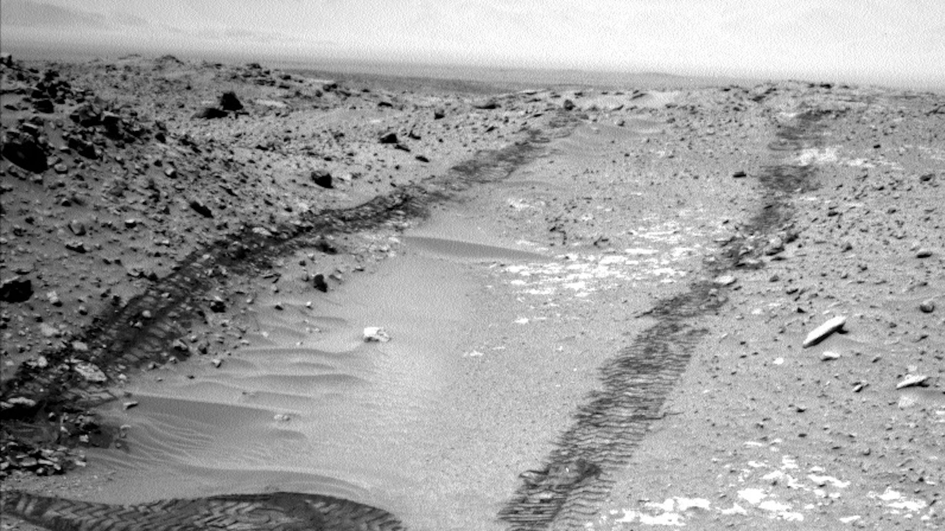 Tracks from the Mars Curiosity rover in black and white.
