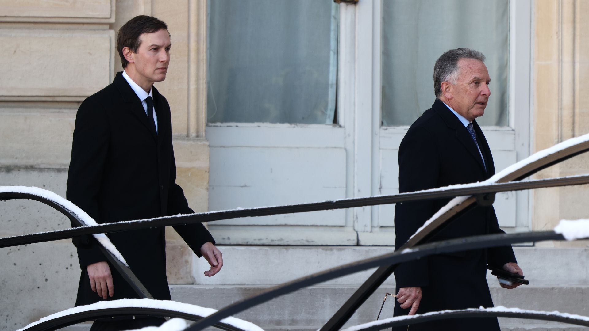 Two men walking in suits in snow