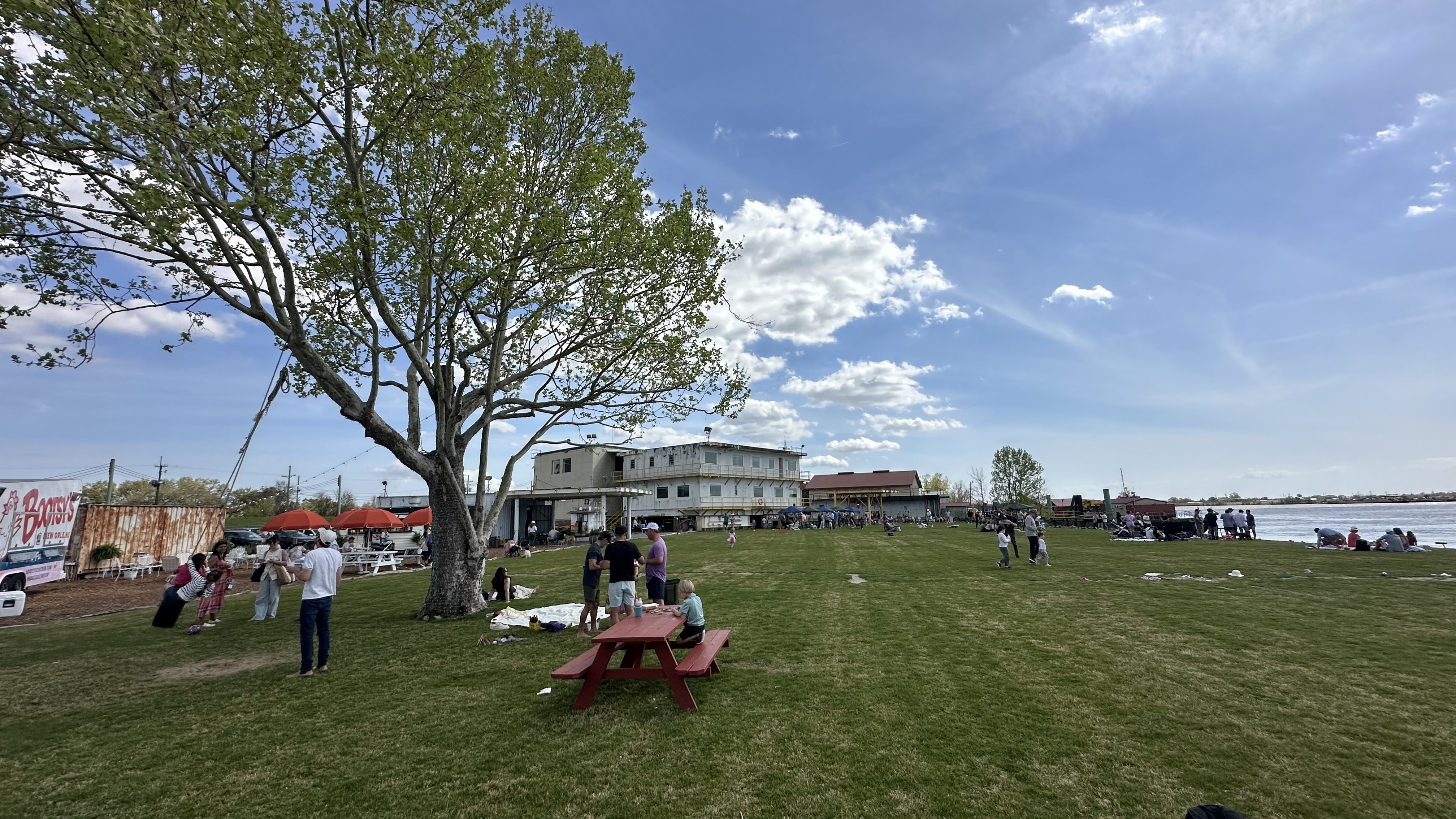 A kid swings on a tire swing while people gather at picnic tables.