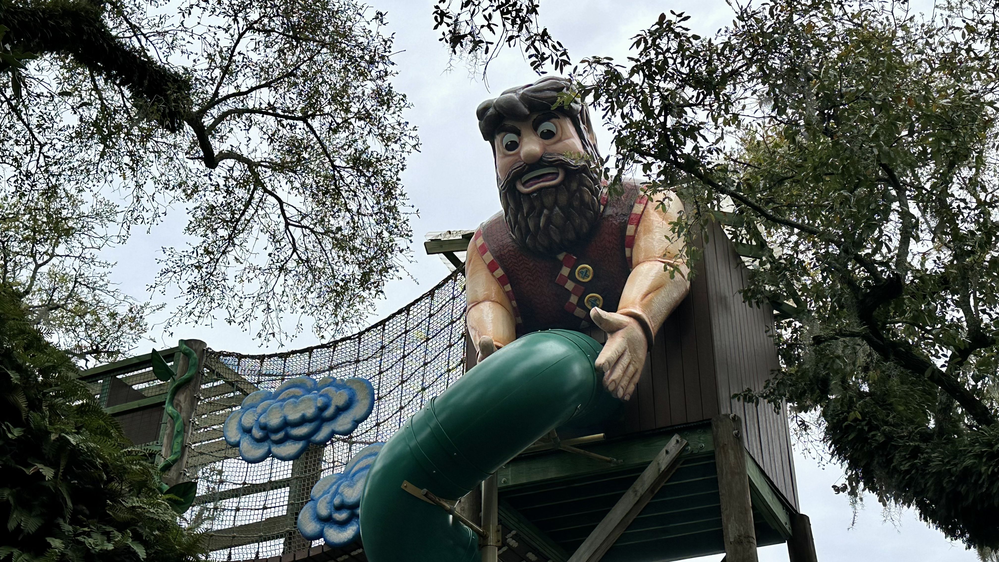 Photo shows the giant from "Jack and the Beanstalk" holding a green slide in what could be construed as a suggestive pose.