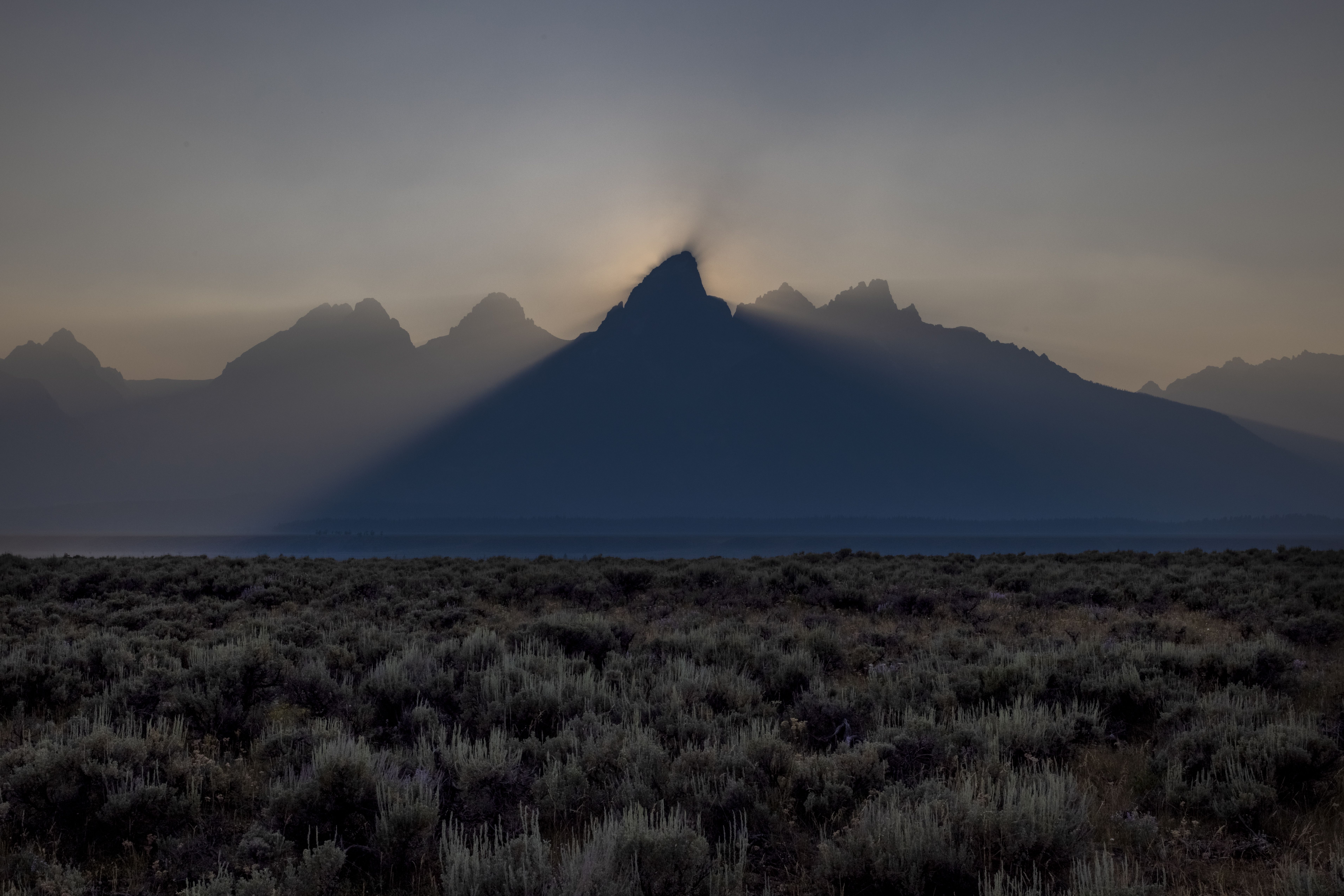 The sun sets behind the Grand Teton peak, shrouded in smoke from regional wildfires July 14, 2021 at Grand Teton National Park. 