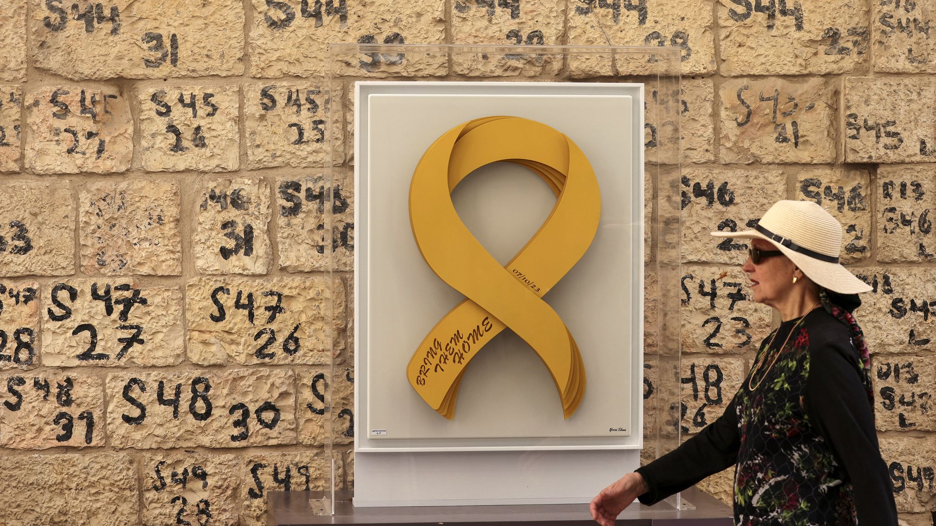 A woman walks past a logo designed to represent the Israeli hostages held in the Gaza Strip