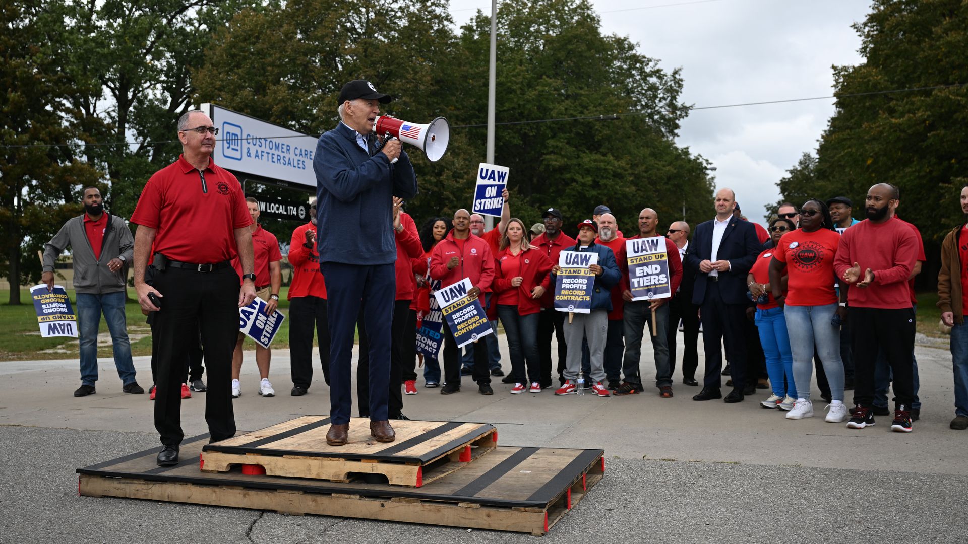 A person with a bullhorn stands on a wooden crate