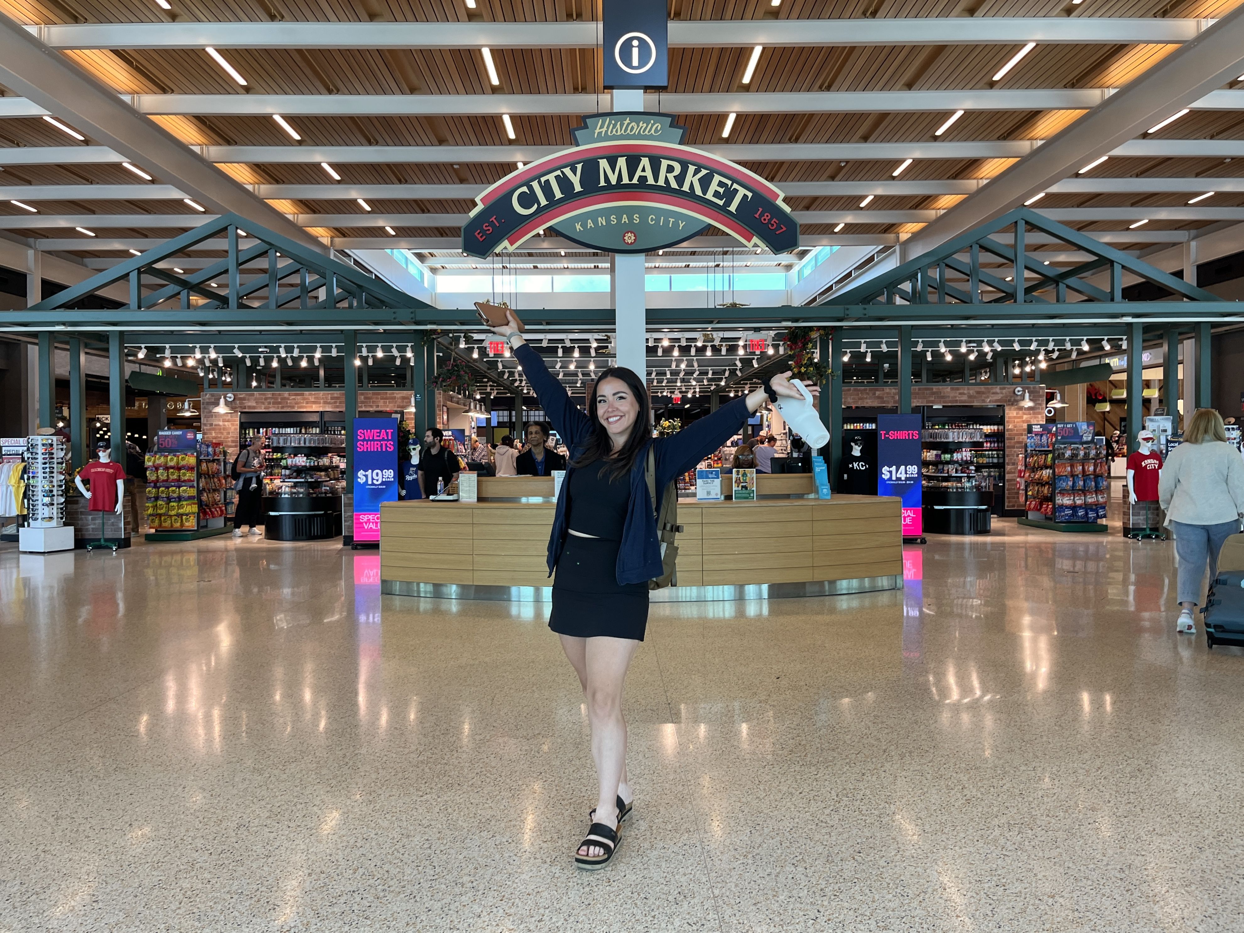 Photo shows reporter Abbey in front of the City Market sign at KCI.
