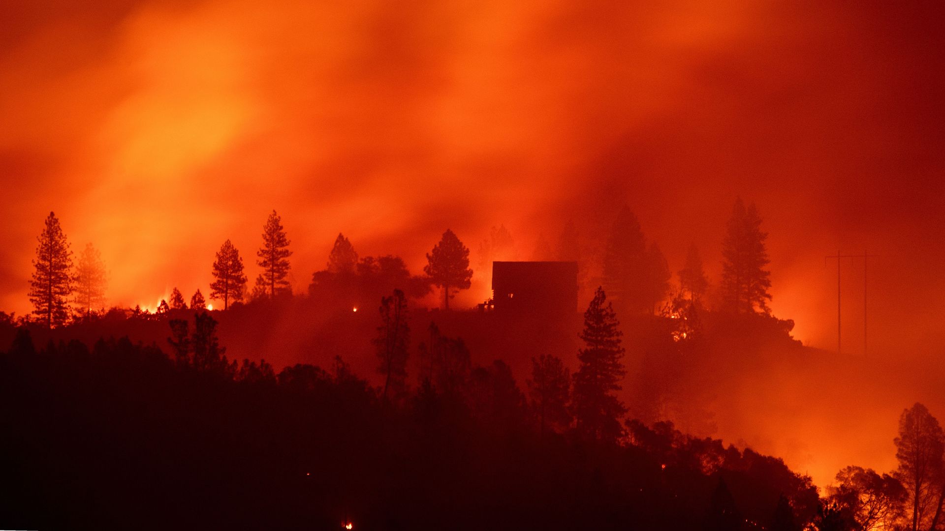 Flames from the Camp fire burn near a home atop a ridge near Big Bend, California