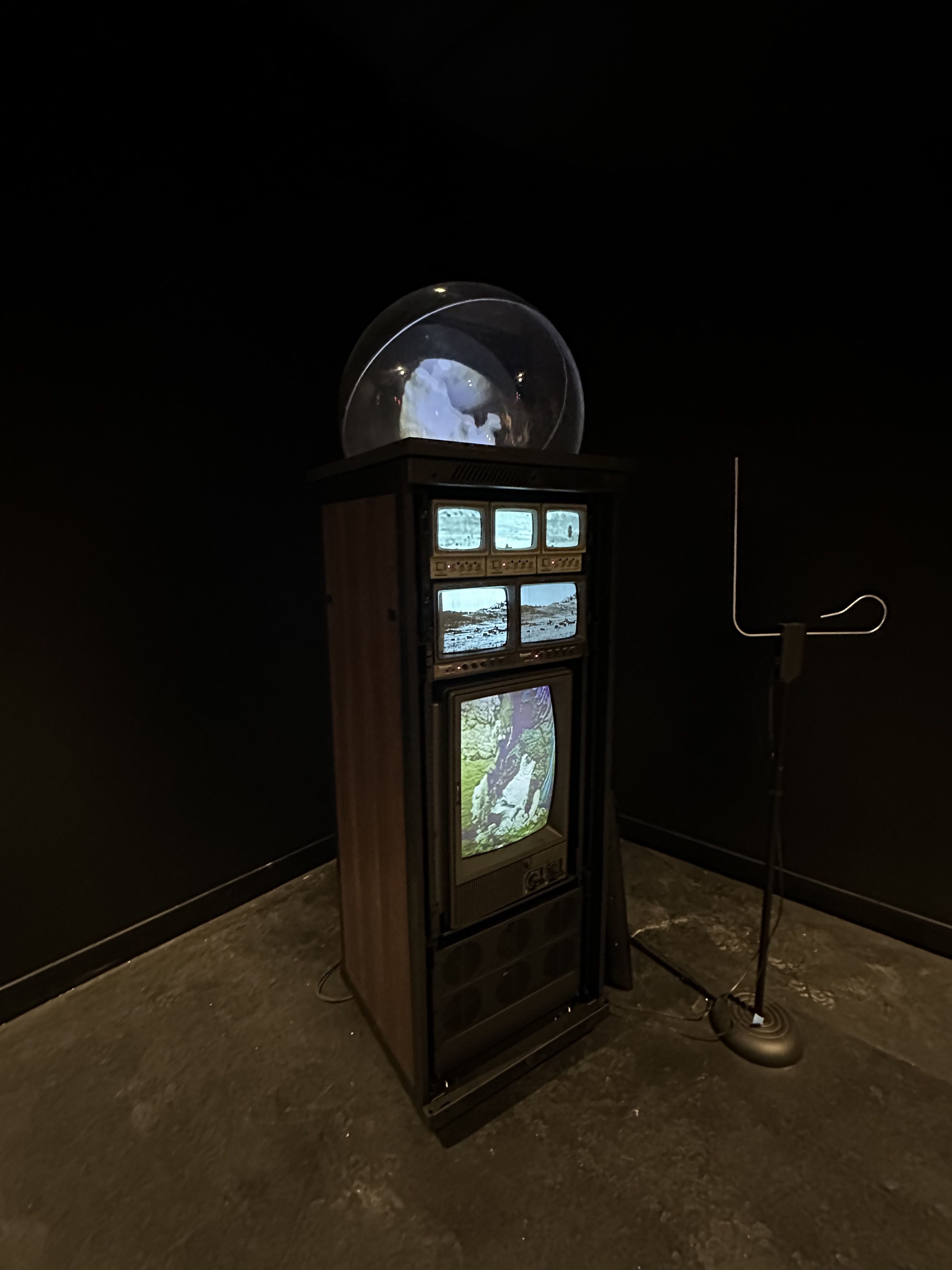 Multiple screens sit on top of each other, with a hologram projector on top, as part of an art exhibit at WNDR Museum in Boston.