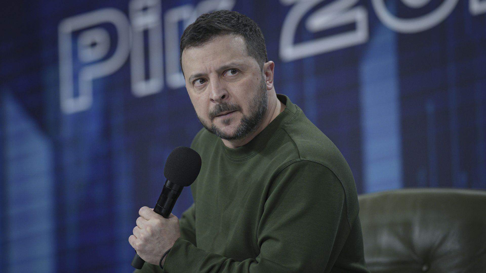 Ukrainian President Volodymyr Zelensky holds a microphone while speaking