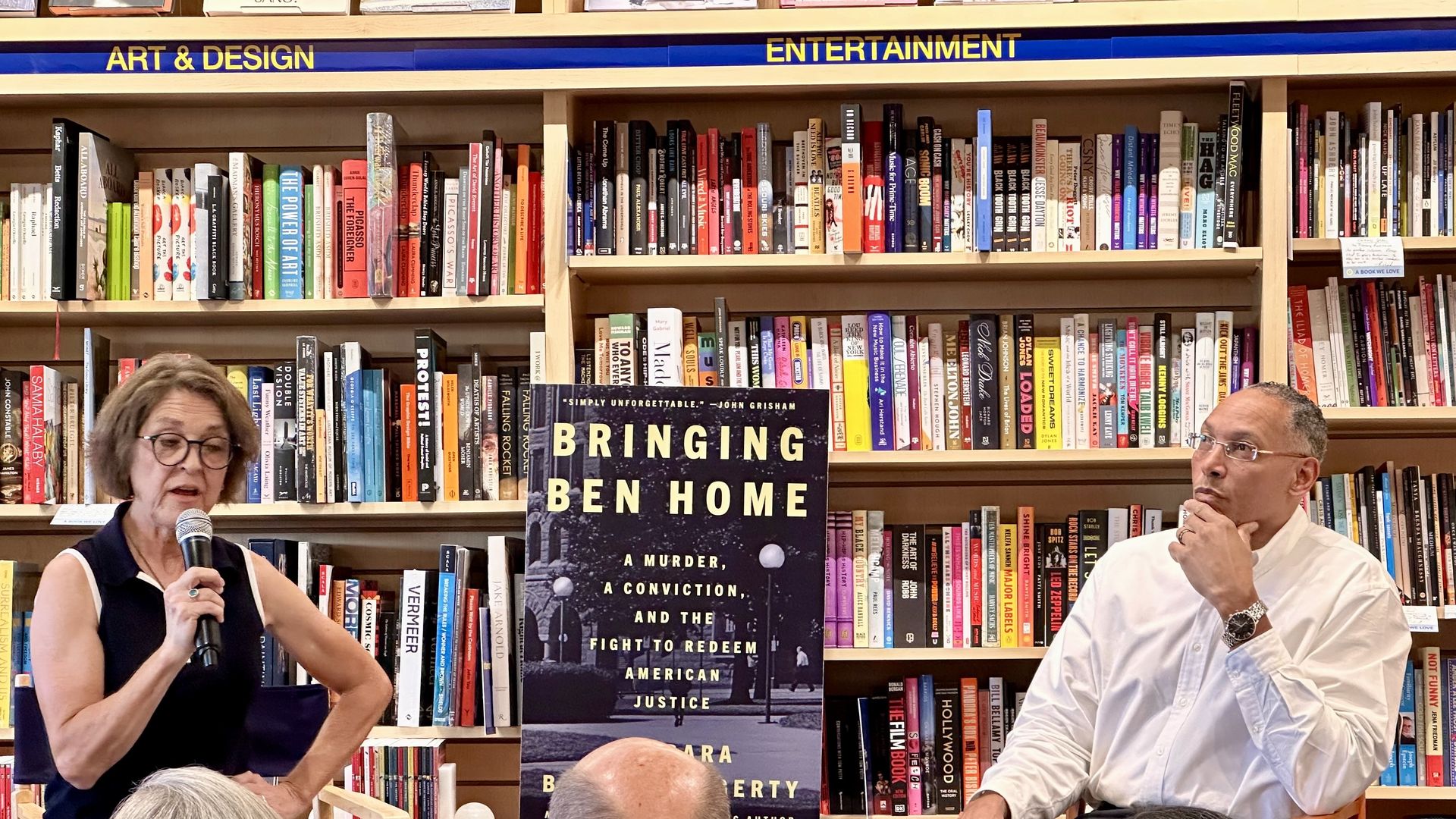 Two people sit in front of a book shelf, with the image of a book titled "Bringing Ben Home" between them 