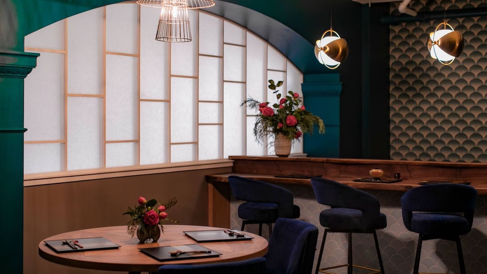A photo of a restaurant's dining room, featuring Art Deco style. A table placement and a counter service setting are visable.