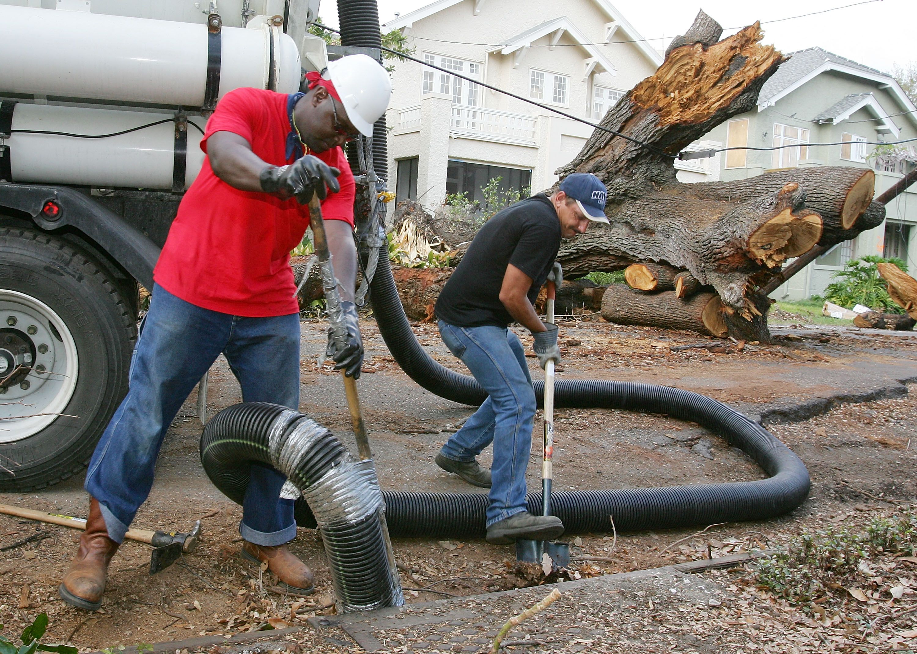 Photo shows two men working in front of a live oak tree that fell during Hurricane Katrina