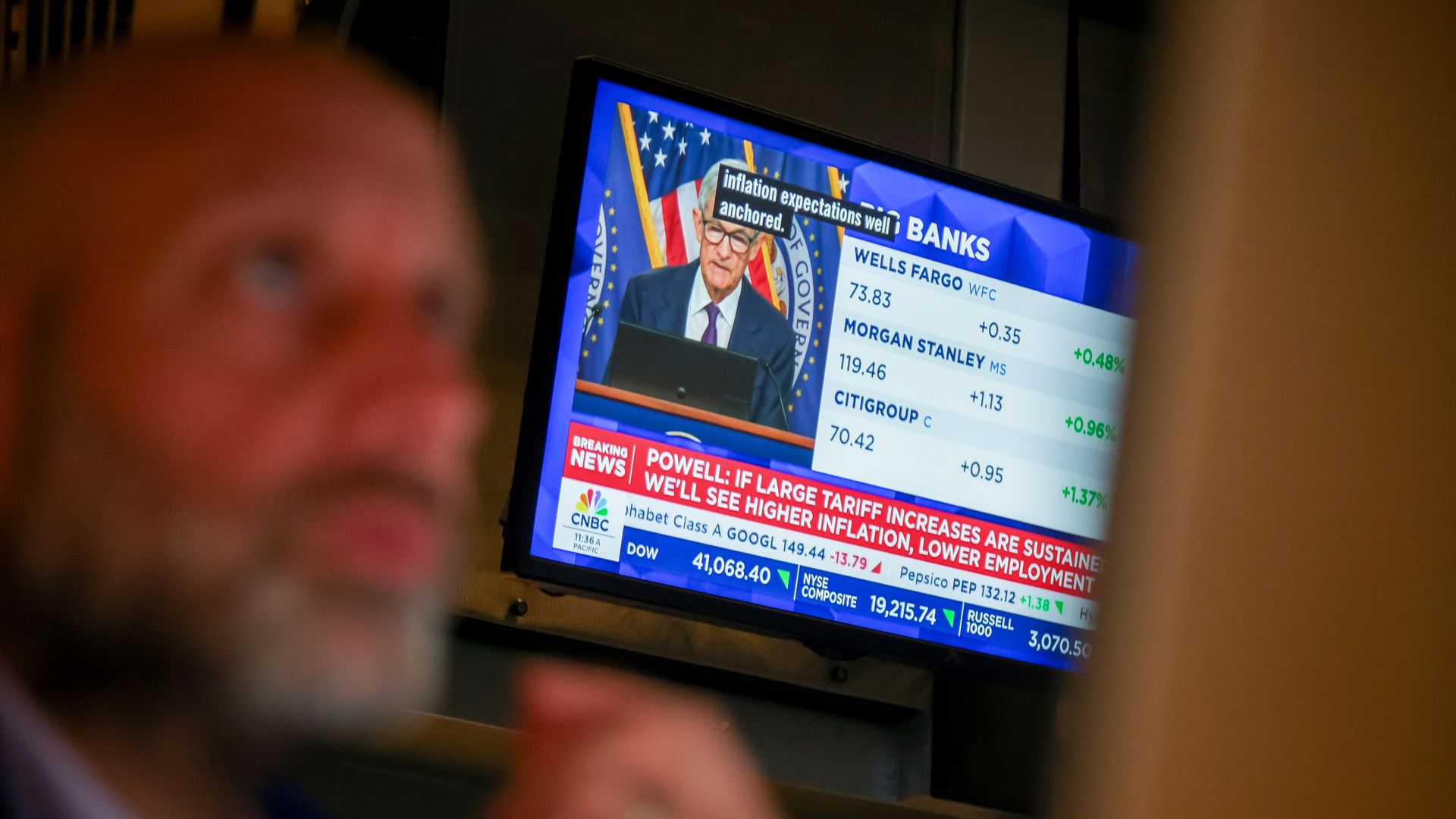 Powell speaking on television with Wall Street trader in the foreground