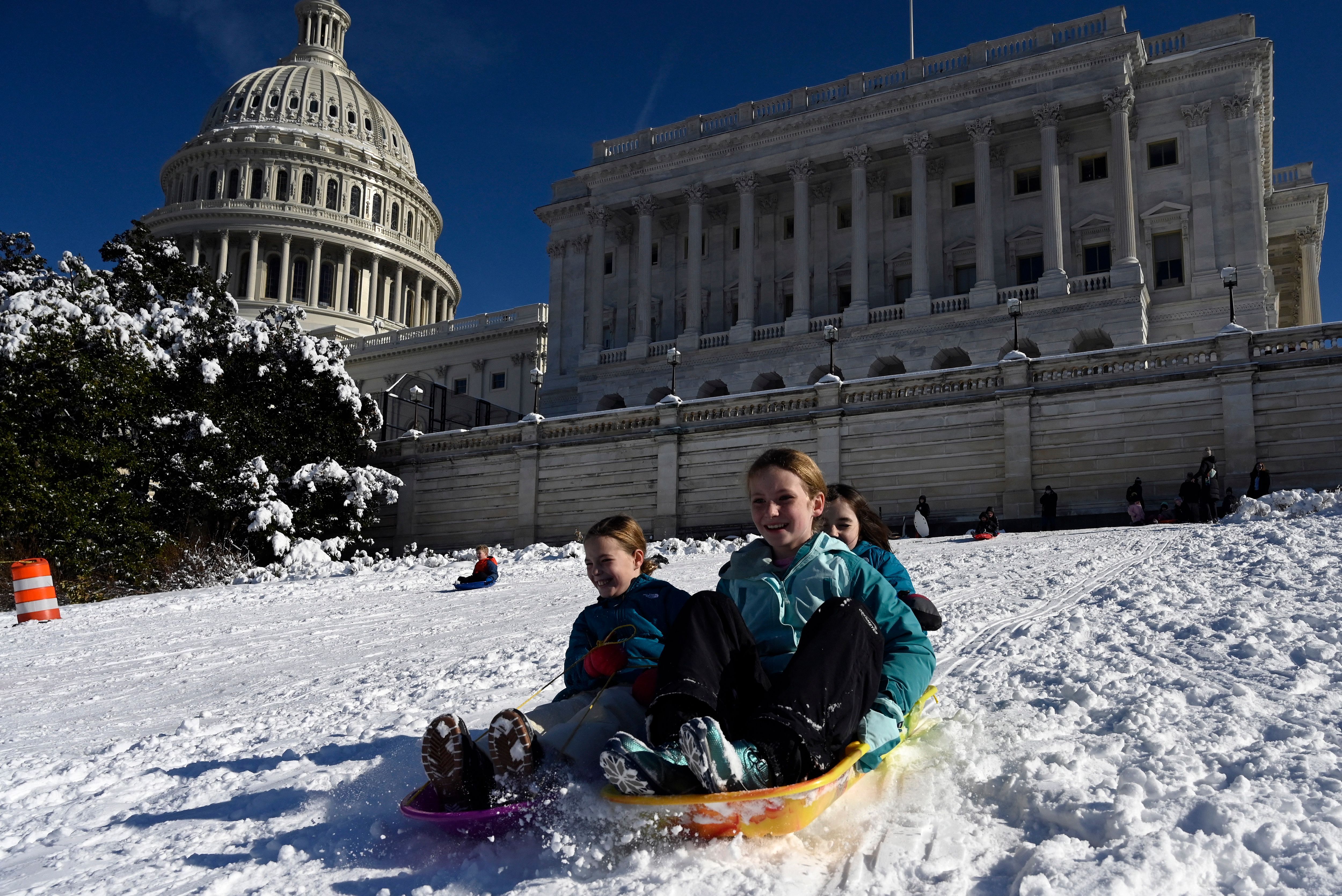 Children sled on the U.S. Capitol front lawn with the building in the background