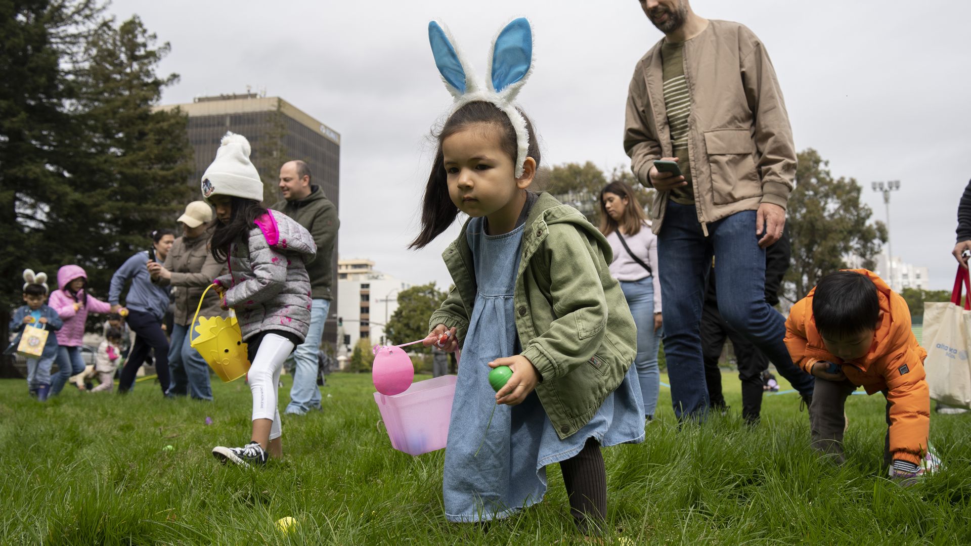 Photo of children and adults wearing bunny ears searching for eggs on an Easter hunt