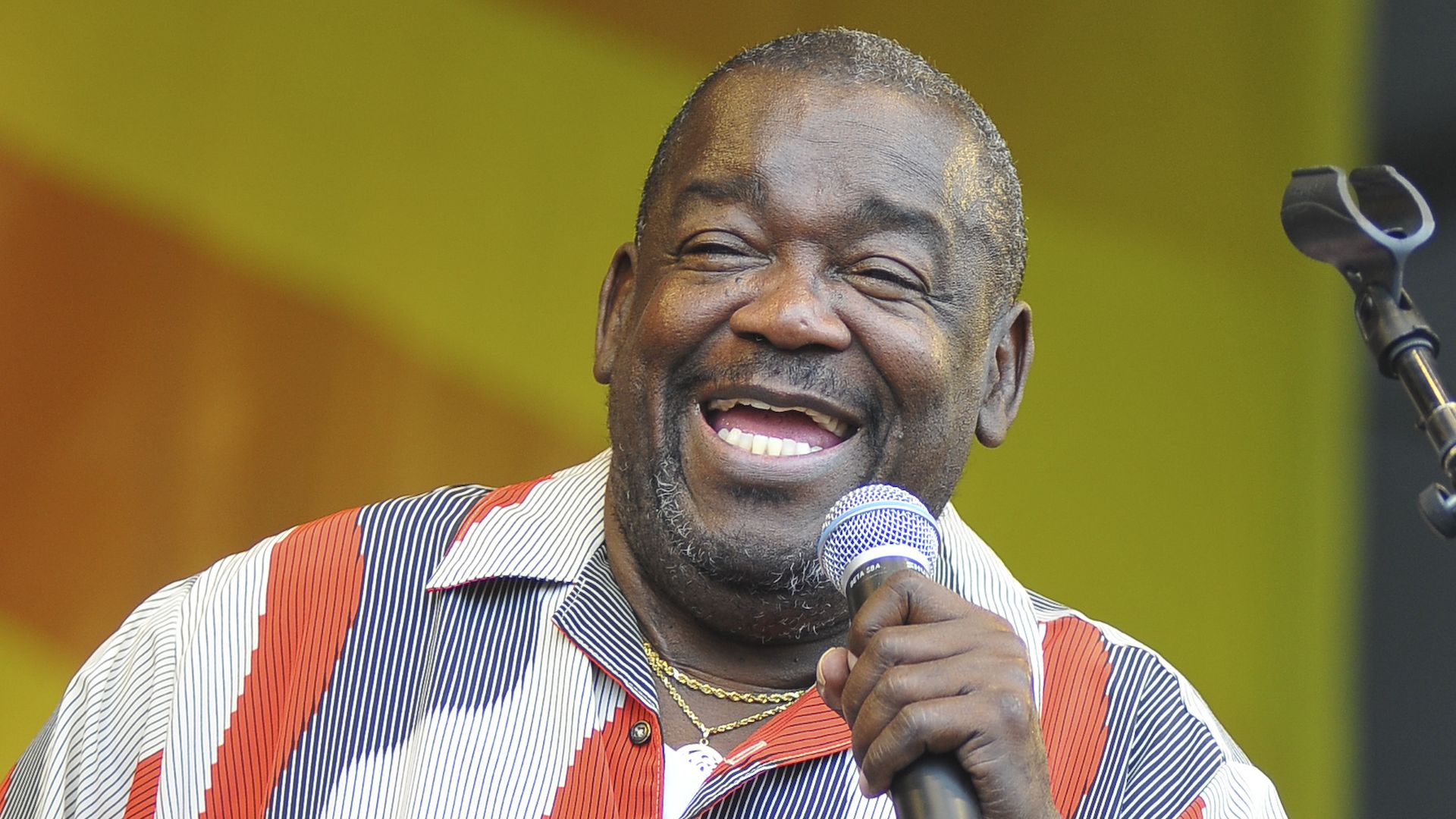 Photo shows Clarence "Frogman" Henry holding a microphone while he sings at Jazz Fest in 2010.