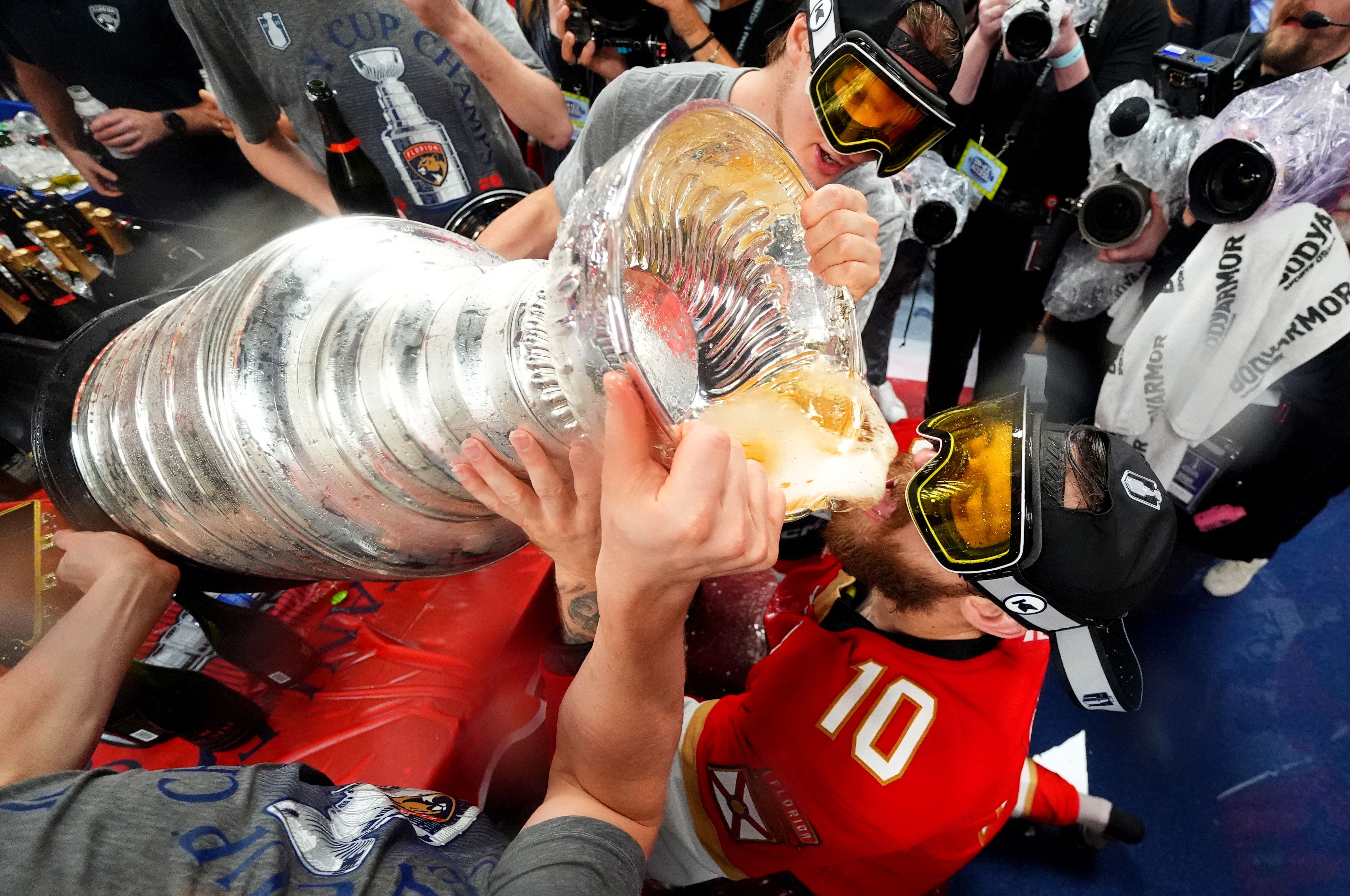 SUNRISE, FLORIDA - JUNE 17: A.J. Greer #10 of the Florida Panthers takes a drink from the Stanley Cup in the locker room after Game Six of the 2025 Stanley Cup Final between the Edmonton Oilers and the Florida Panthers at Amerant Bank Arena on June 17, 2025 in Sunrise, Florida. The Panthers won the 