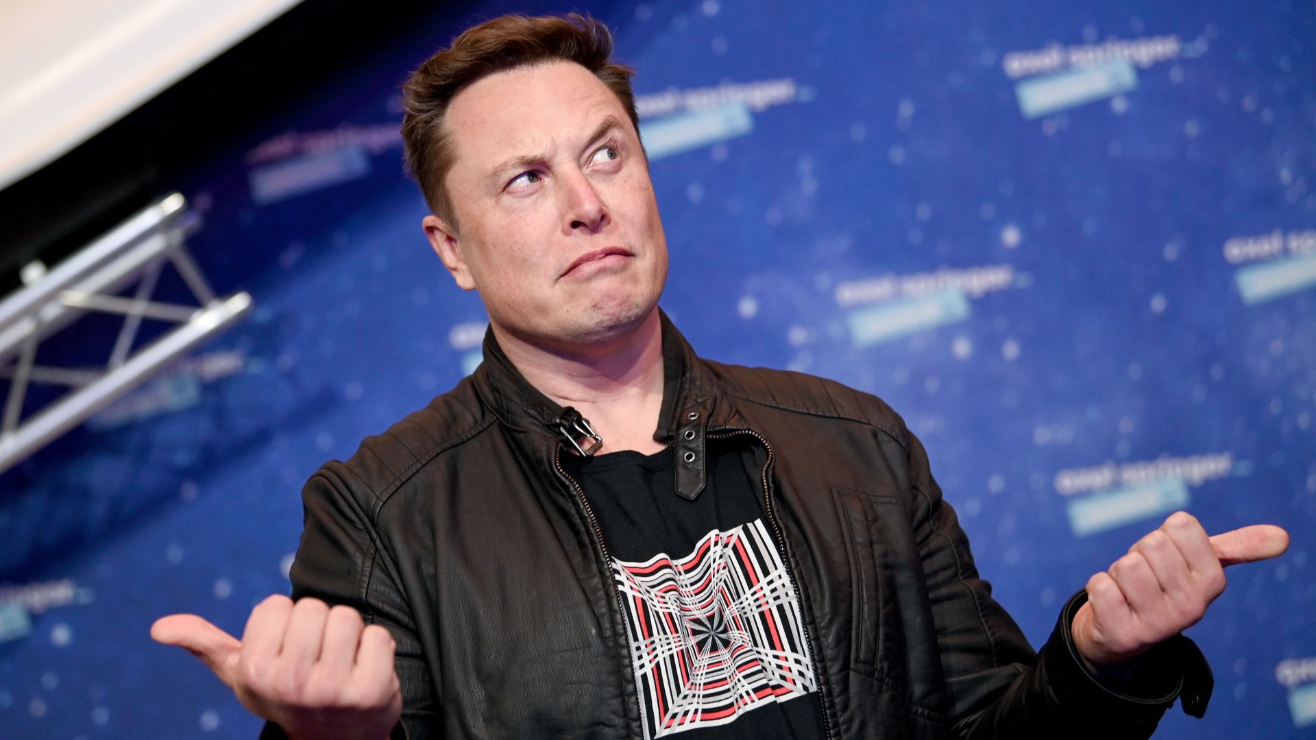 Elon Musk poses for photos with two thumbs up and a quizzical look