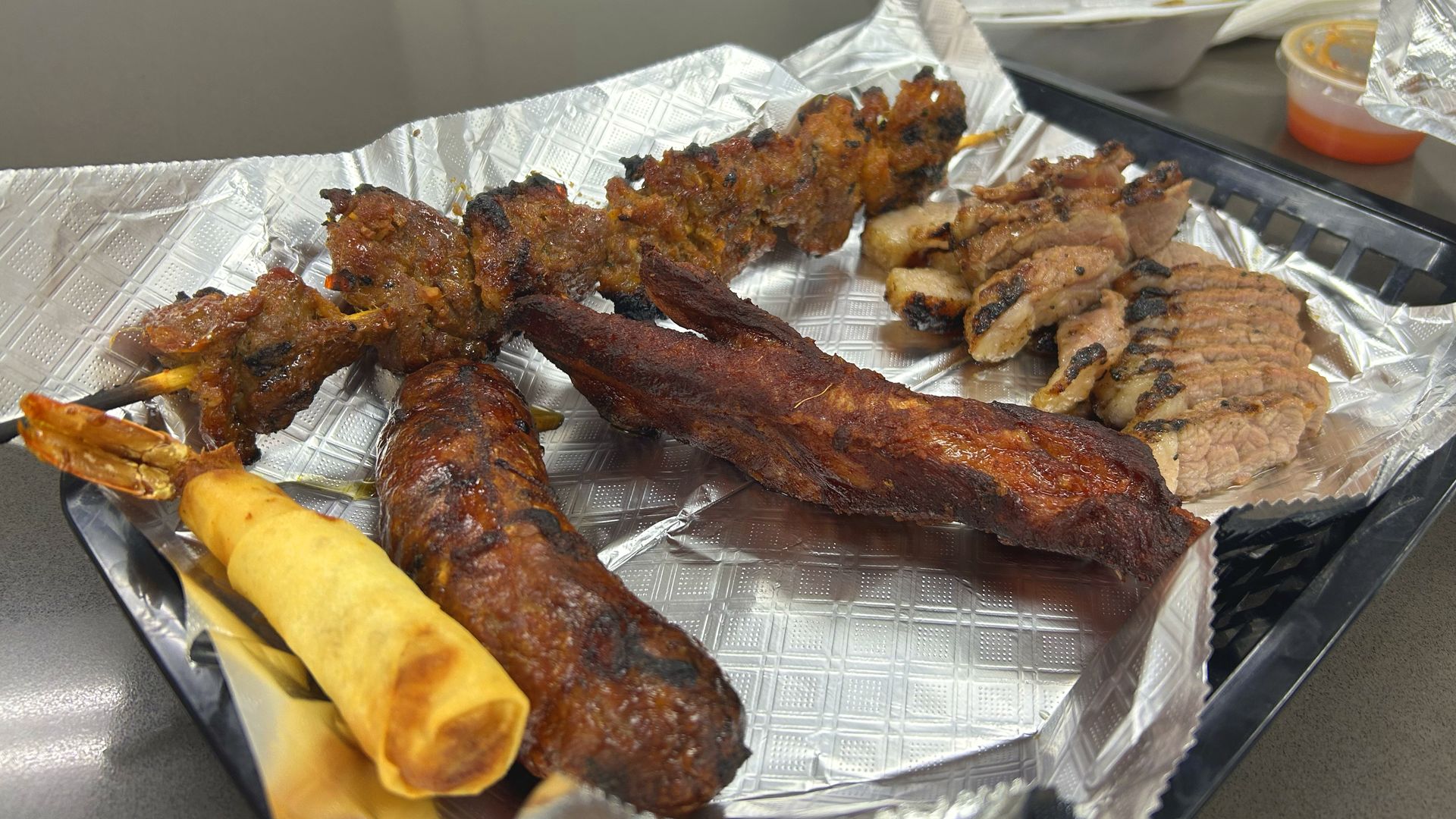 A full Cambodian BBQ spread for under $20: ribs, sausage, brisket, a shrimp roll, and a beef skewer, all smoky, juicy, and packed with flavor.
