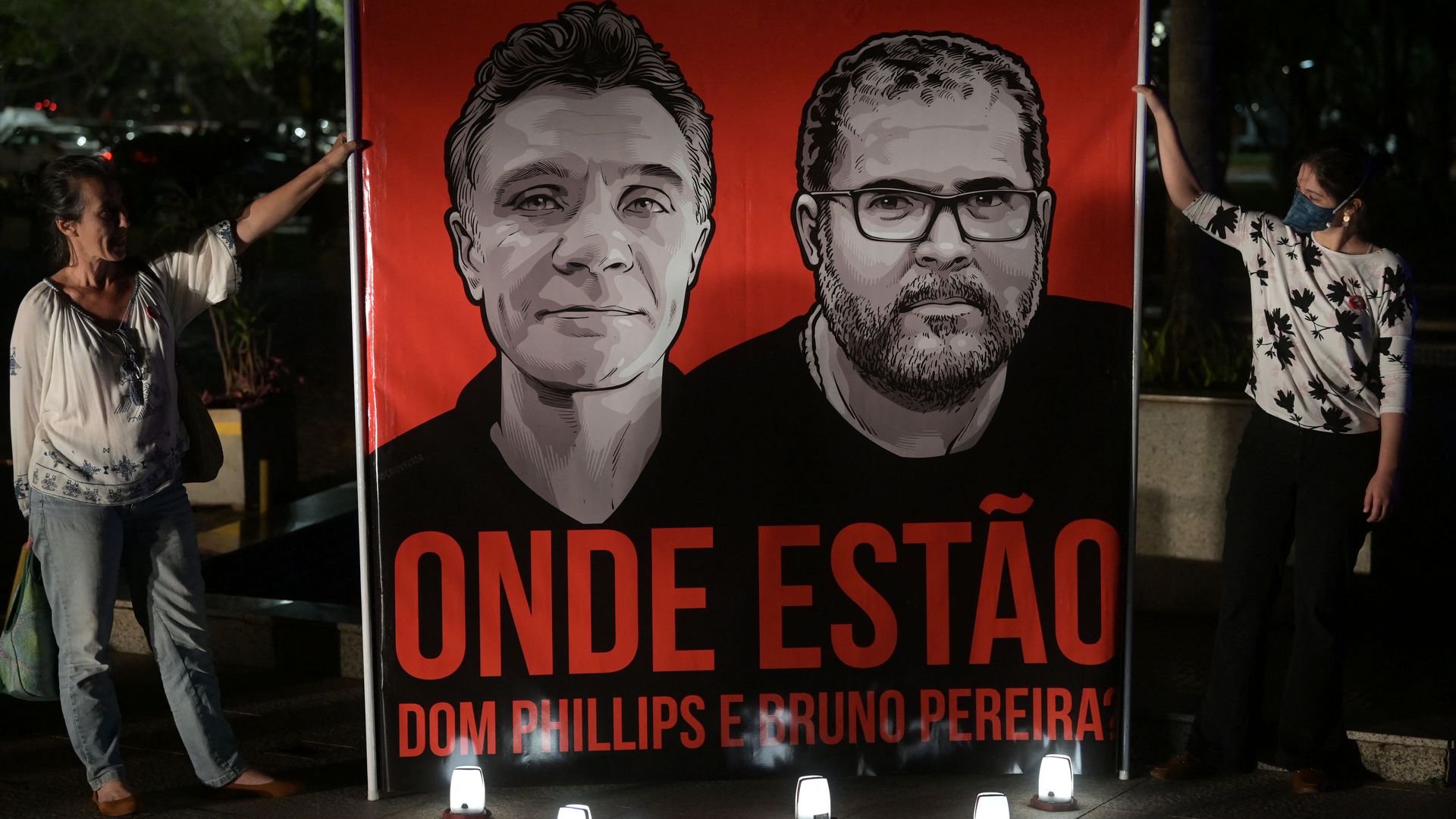 People holding a mural of British journalist Dom Phillips and Brazilian Indigenous affairs specialist Bruno Pereira during a vigil in Brasilia, on June 9.