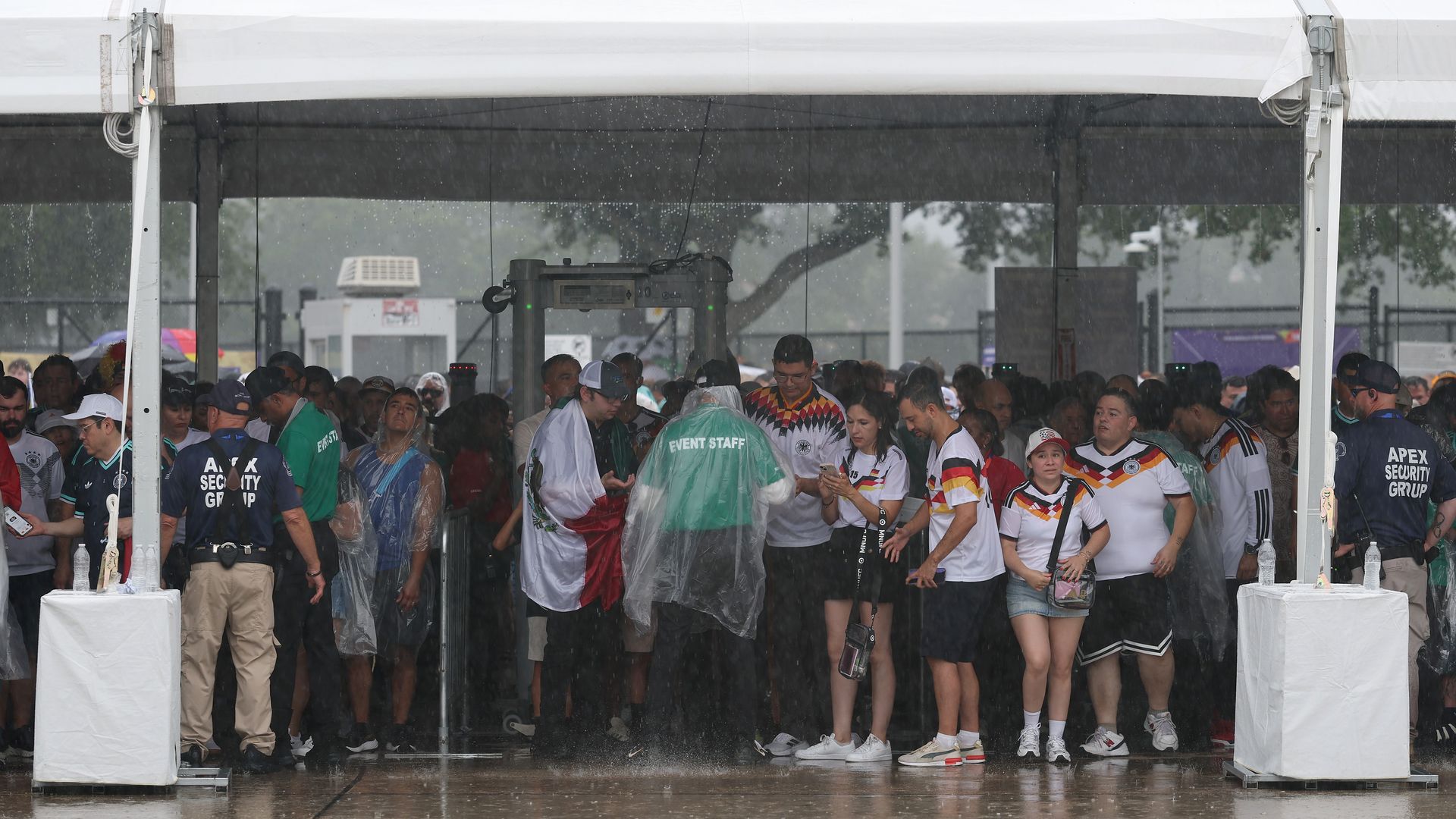 Soccer fans huddle under a tent outside Houston Stadium during a downpour before a World Cup match