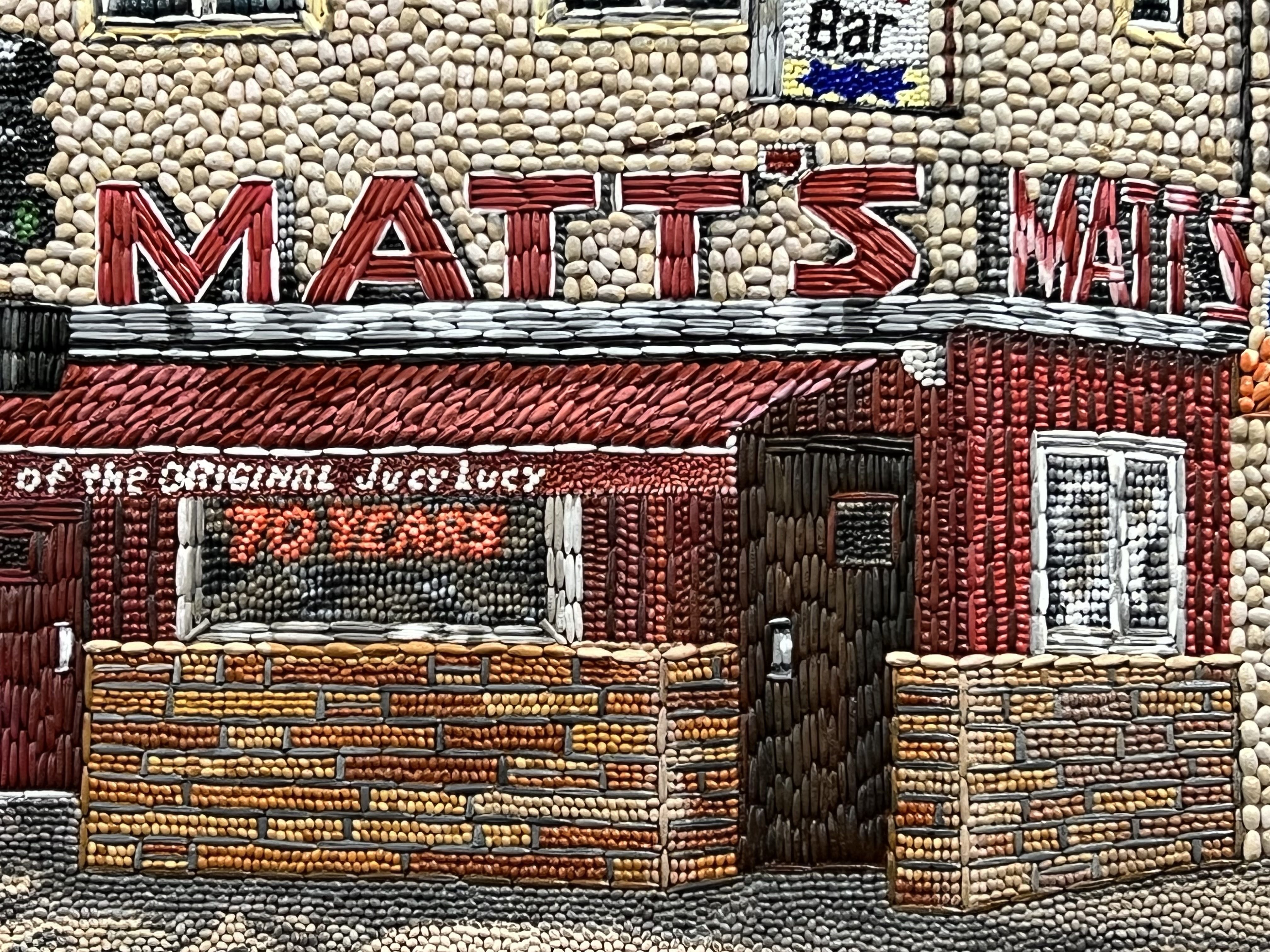 A seed art depiction of Matt's Bar in South Minneapolis, featuring a maroon awning reading "of the original Jucy Lucy," made of barley, clover, rye, wild rice and canola.