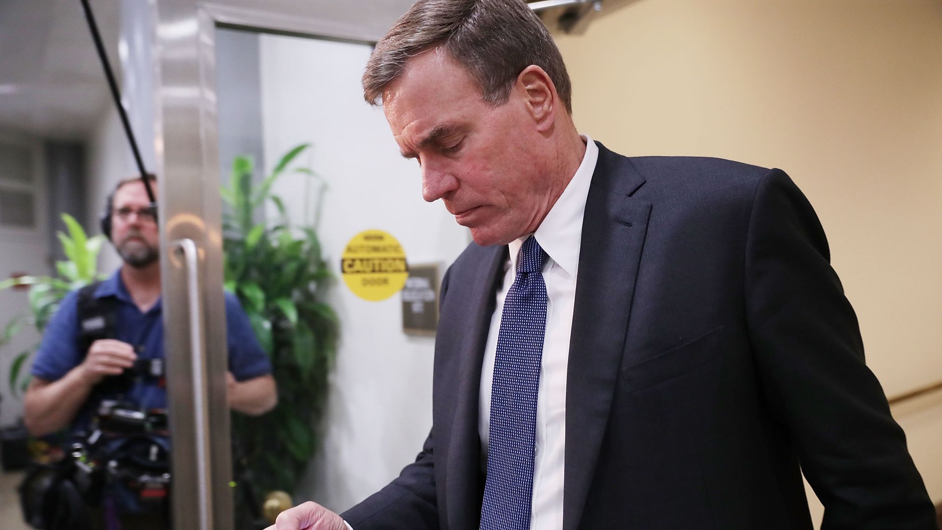 Sen. Mark Warner looks at a smartphone