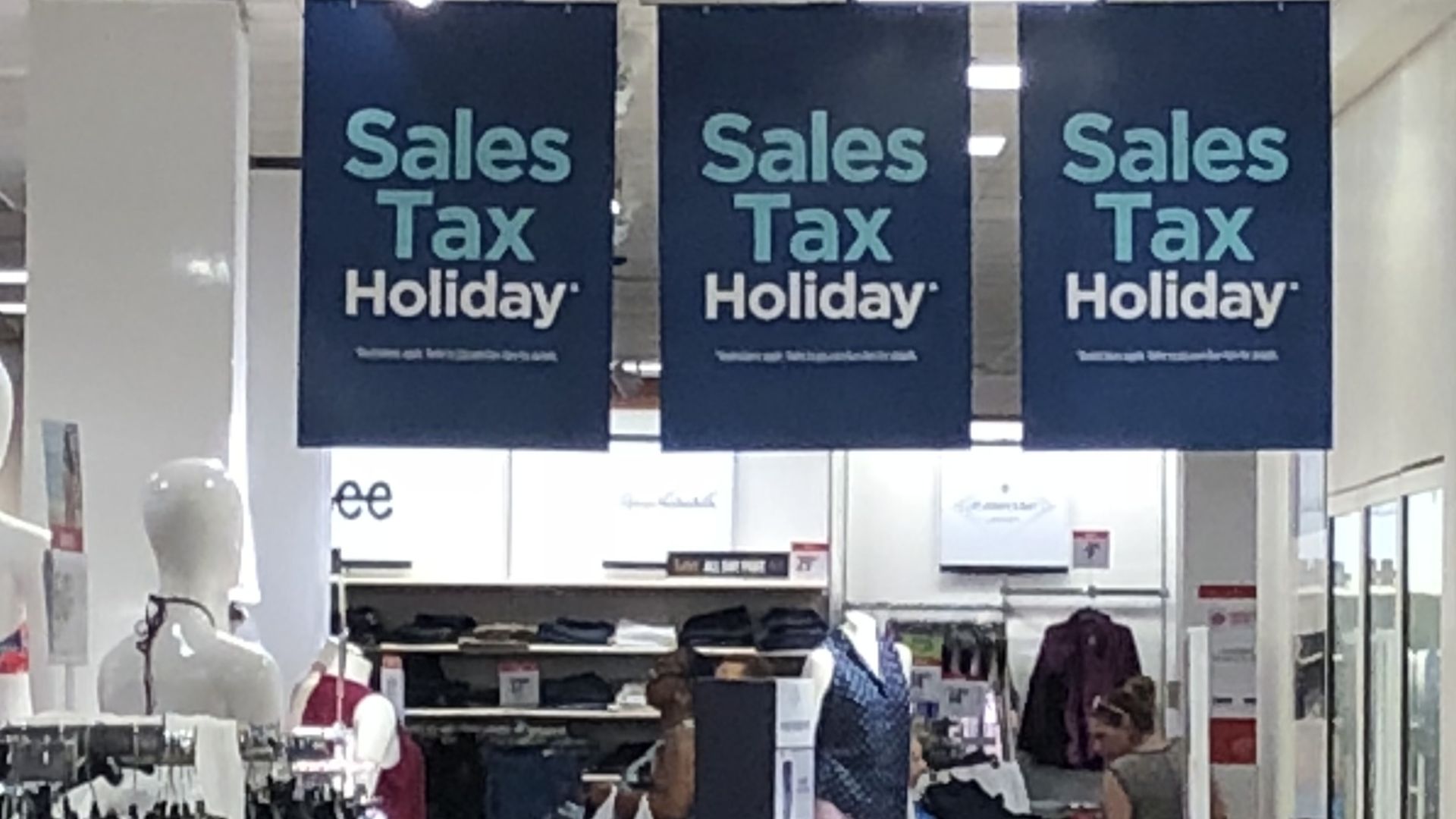 Sales tax holiday signs hang in a store 