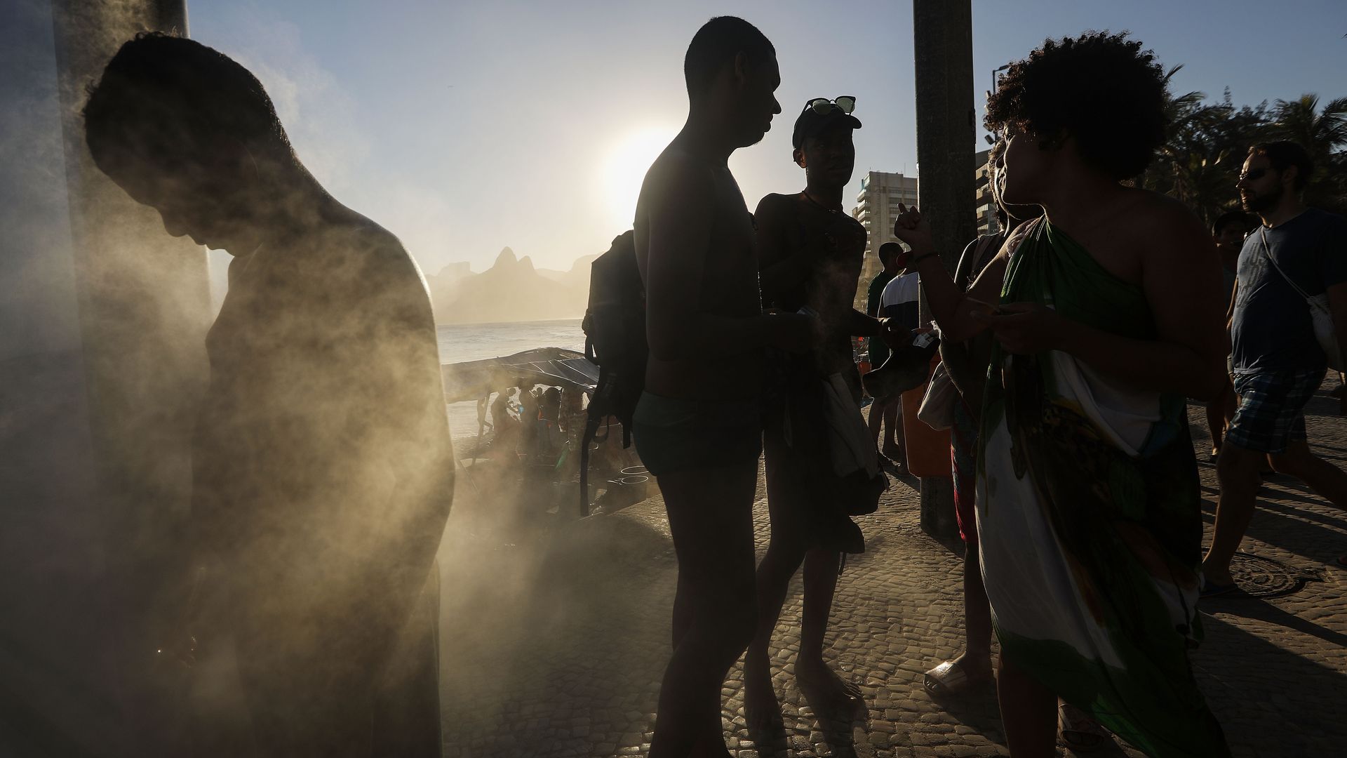 People gather by a cooling station on a hot winter day on Ipanema beach on the Atlantic Ocean.