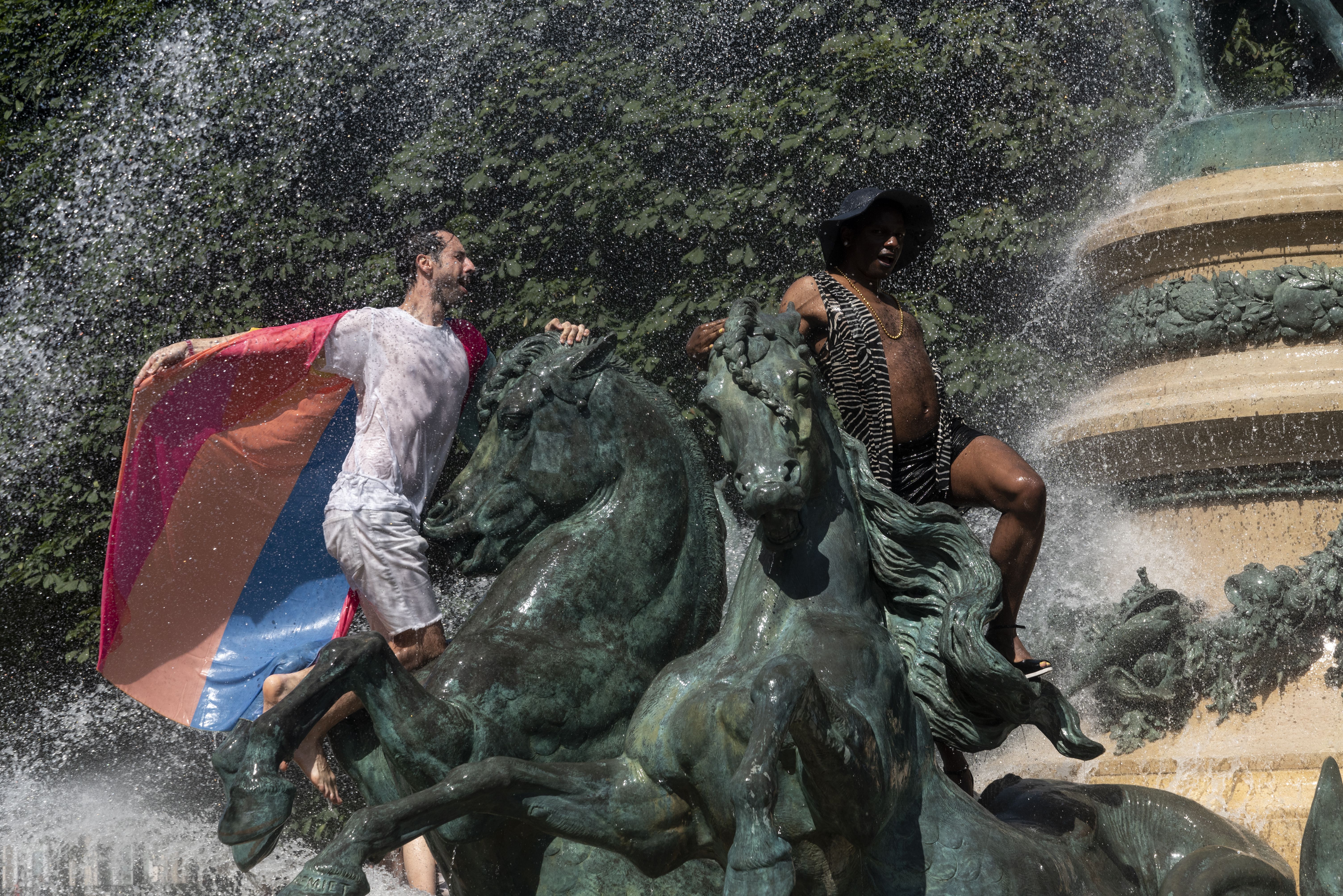 Pride-goers in Paris cool off in a fountain in a bid to beat the searing heat. 