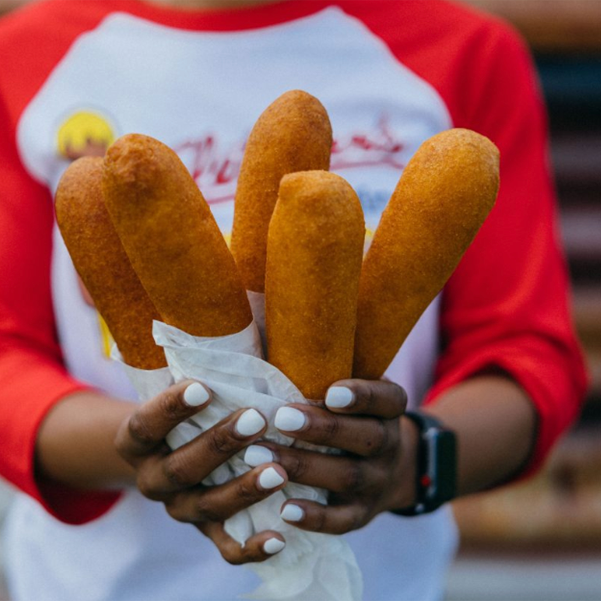 a person holds a bundle of corn dogs
