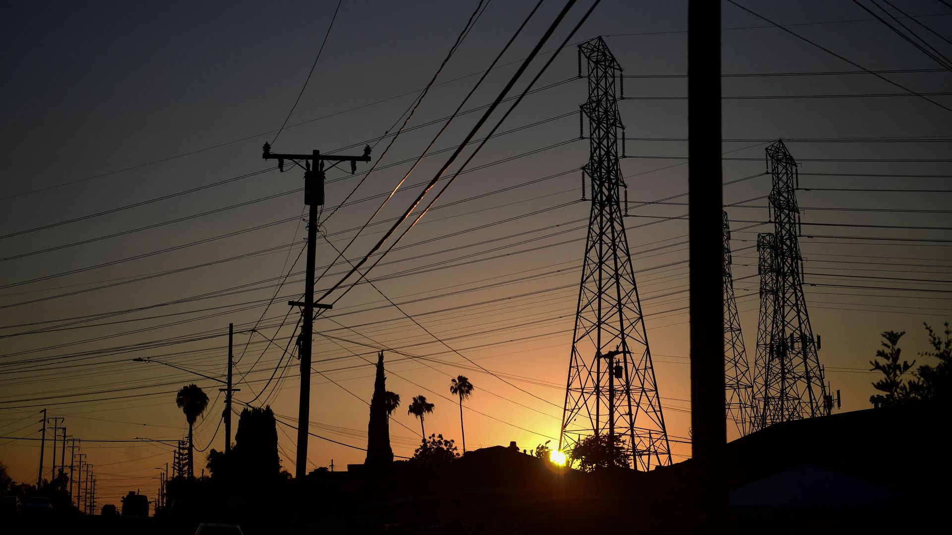 Sun low on horizon beneath power lines.