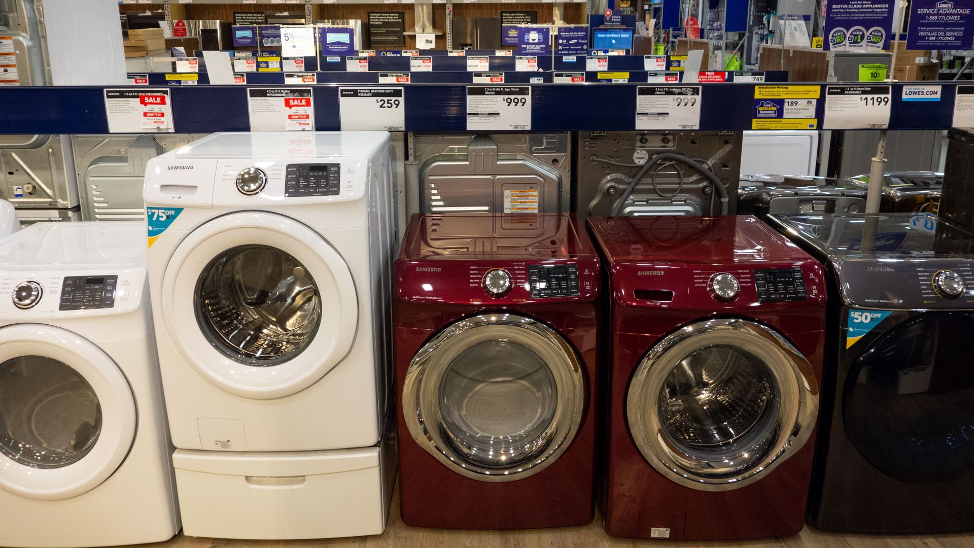 In this image, a row of different colors and brands of washing machines sit in a store.