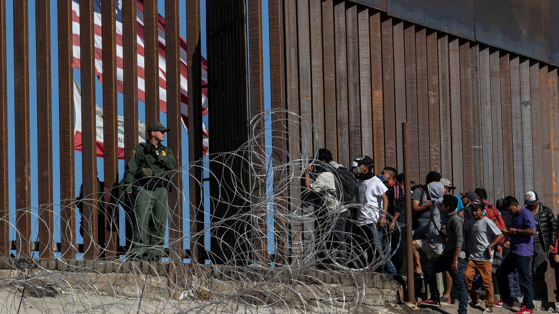Central American migrants look through a border fence as a US Border PatRol agents stands guard near the El Chaparral border crossing in Tijuana, Baja California State, Mexico, on November 25.