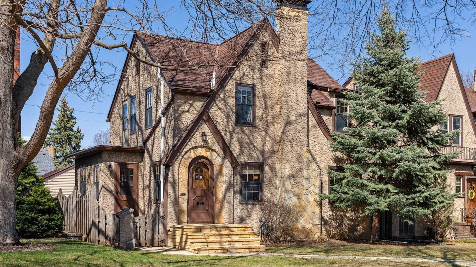 exterior of Tudor-style home with stone steps and large trees