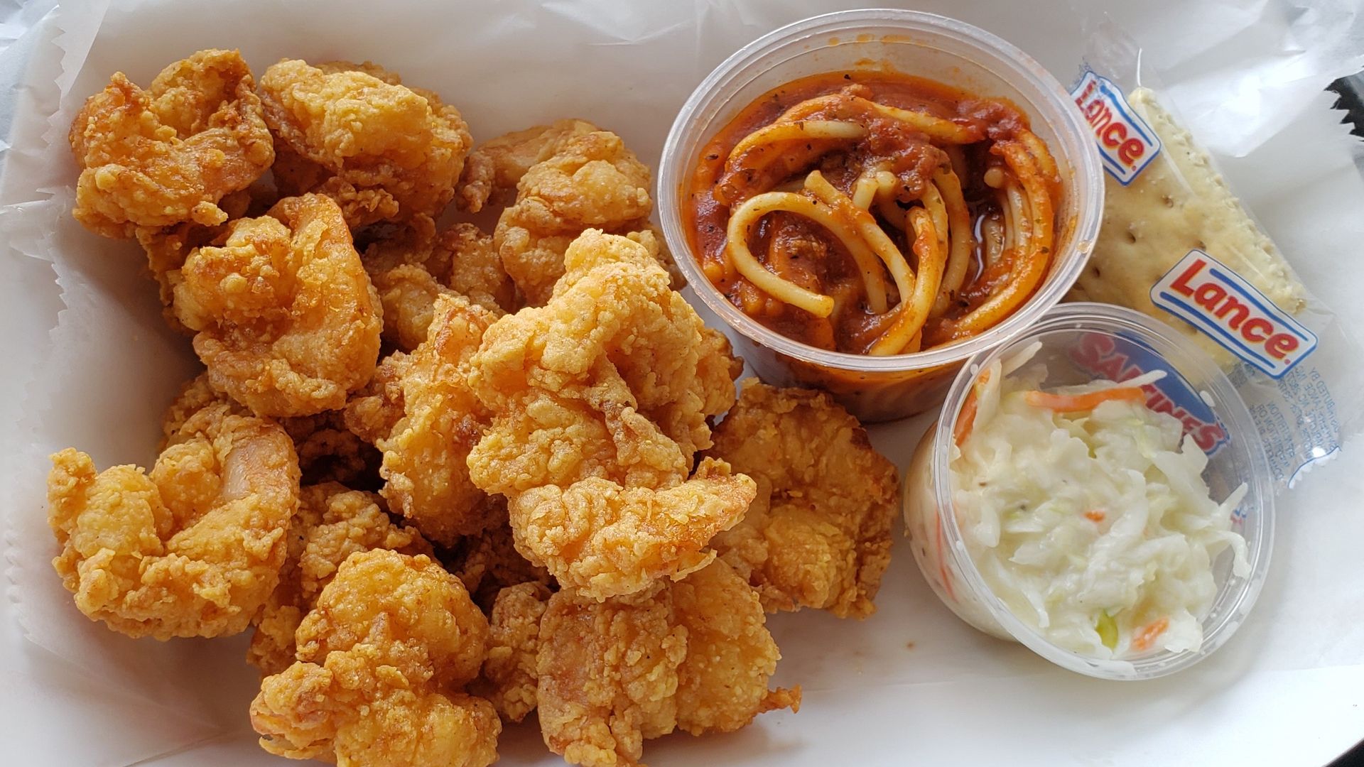 Fried shrimp served with a side of spaghetti and coleslaw. 