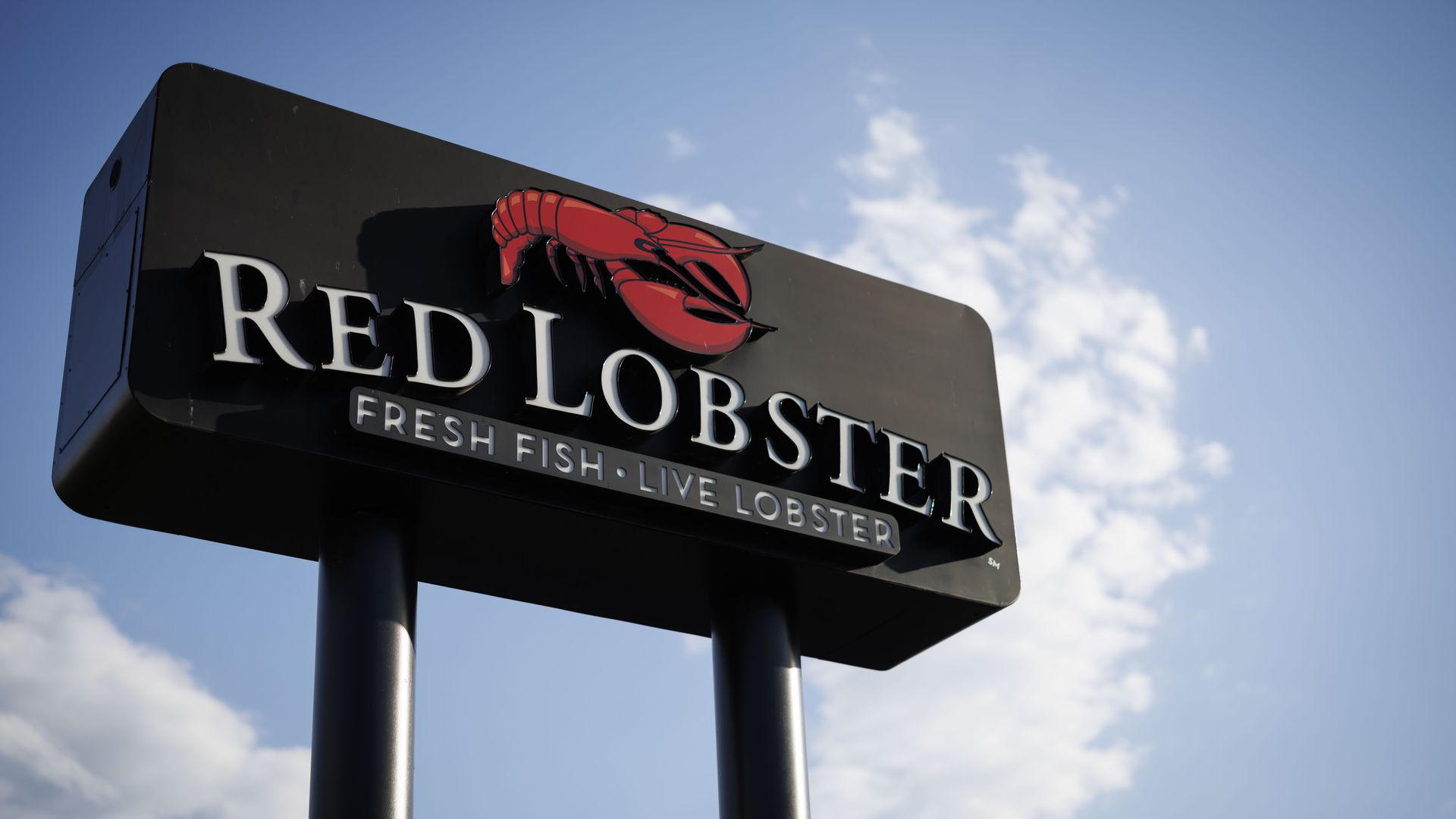 A Red Lobster sign juts into a blue sky.