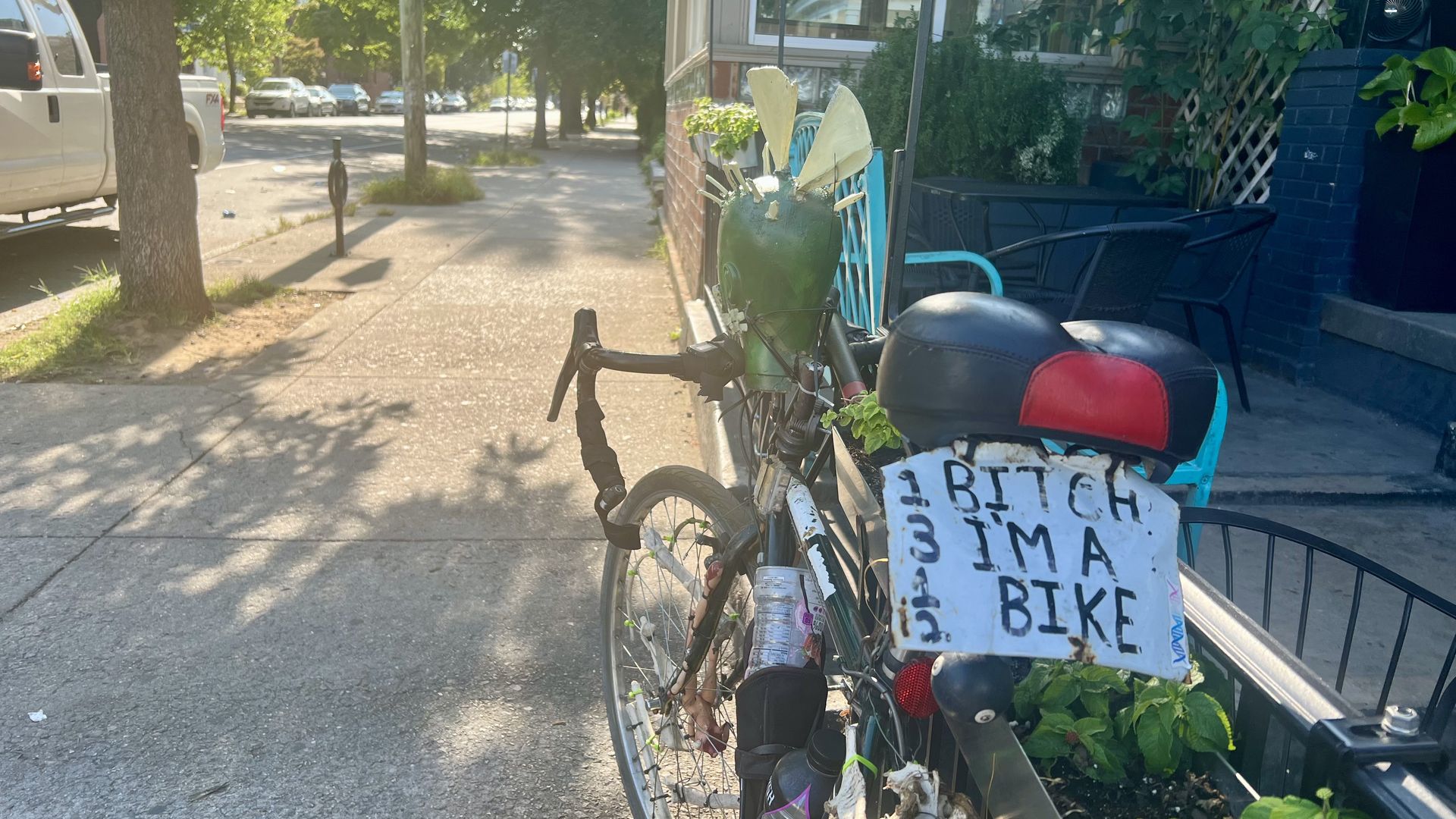 a sidewalk and a bike with a fake license plate that says "bitch I'm a bike" in black letters.
