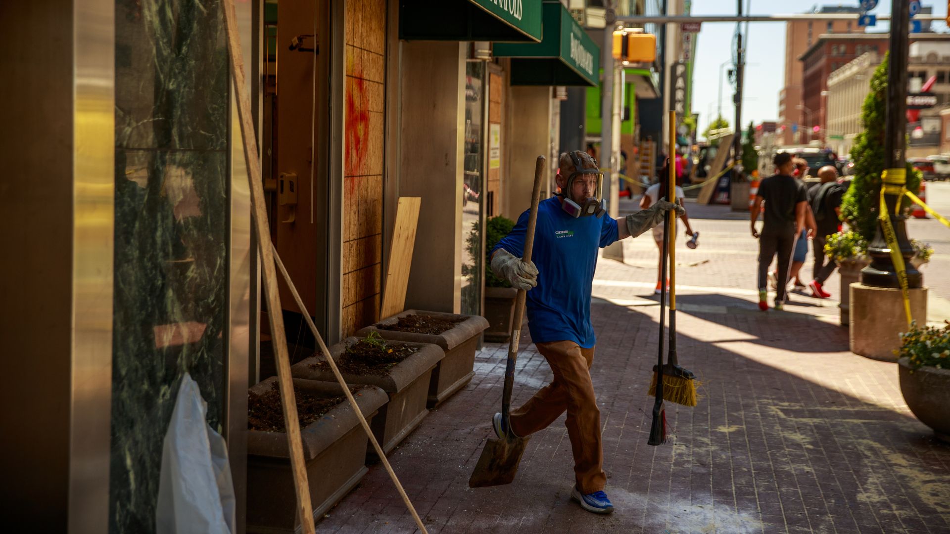 A worker cleans up glass at the Bank of Indianapolis after the riots on May 31, 2020.