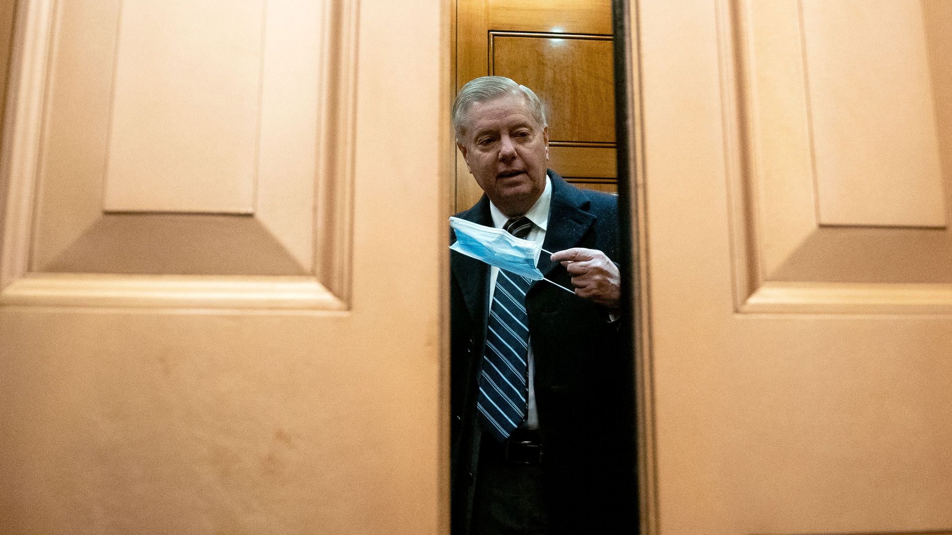 Lindsey Graham holds a face mask while standing in an elevator
