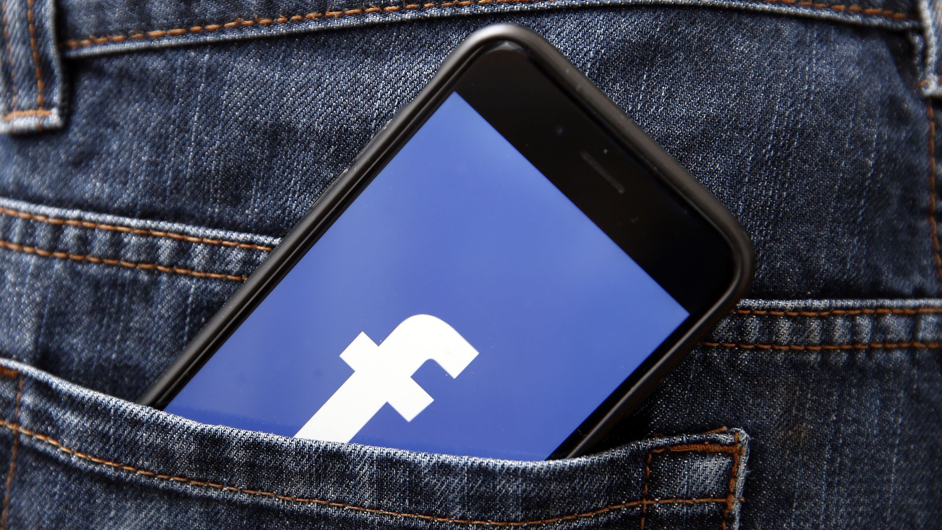 An image of a phone with the Facebook logo in a jeans pocket