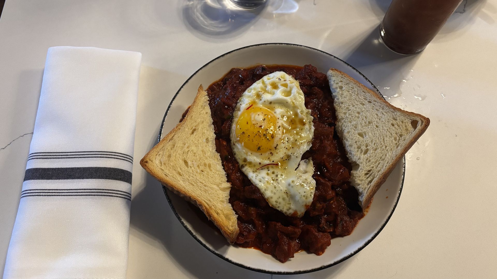 A bowl of food topped with eggs and toast.
