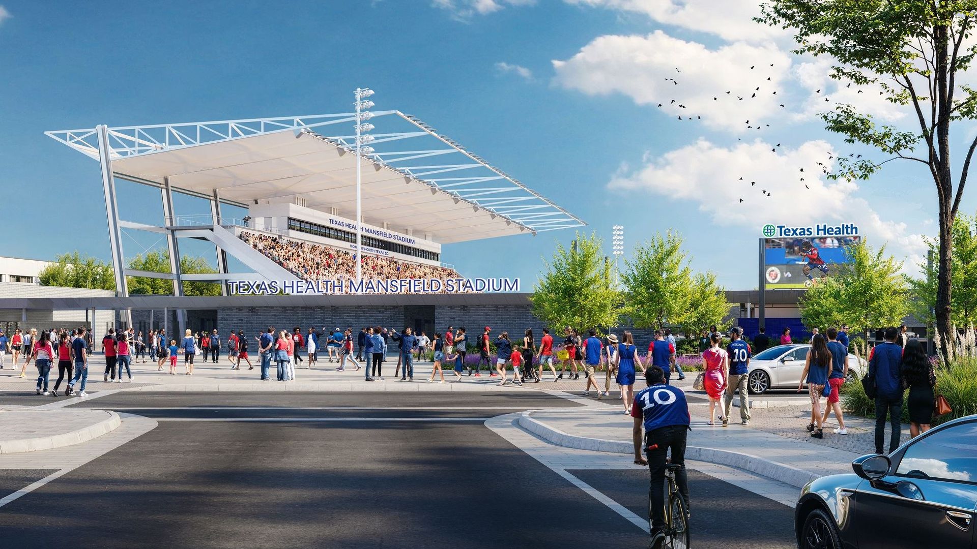 Crowd of people in red and blue walking toward Texas Health Mansfield Stadium on a sunny day with a blue sky and scattered clouds.