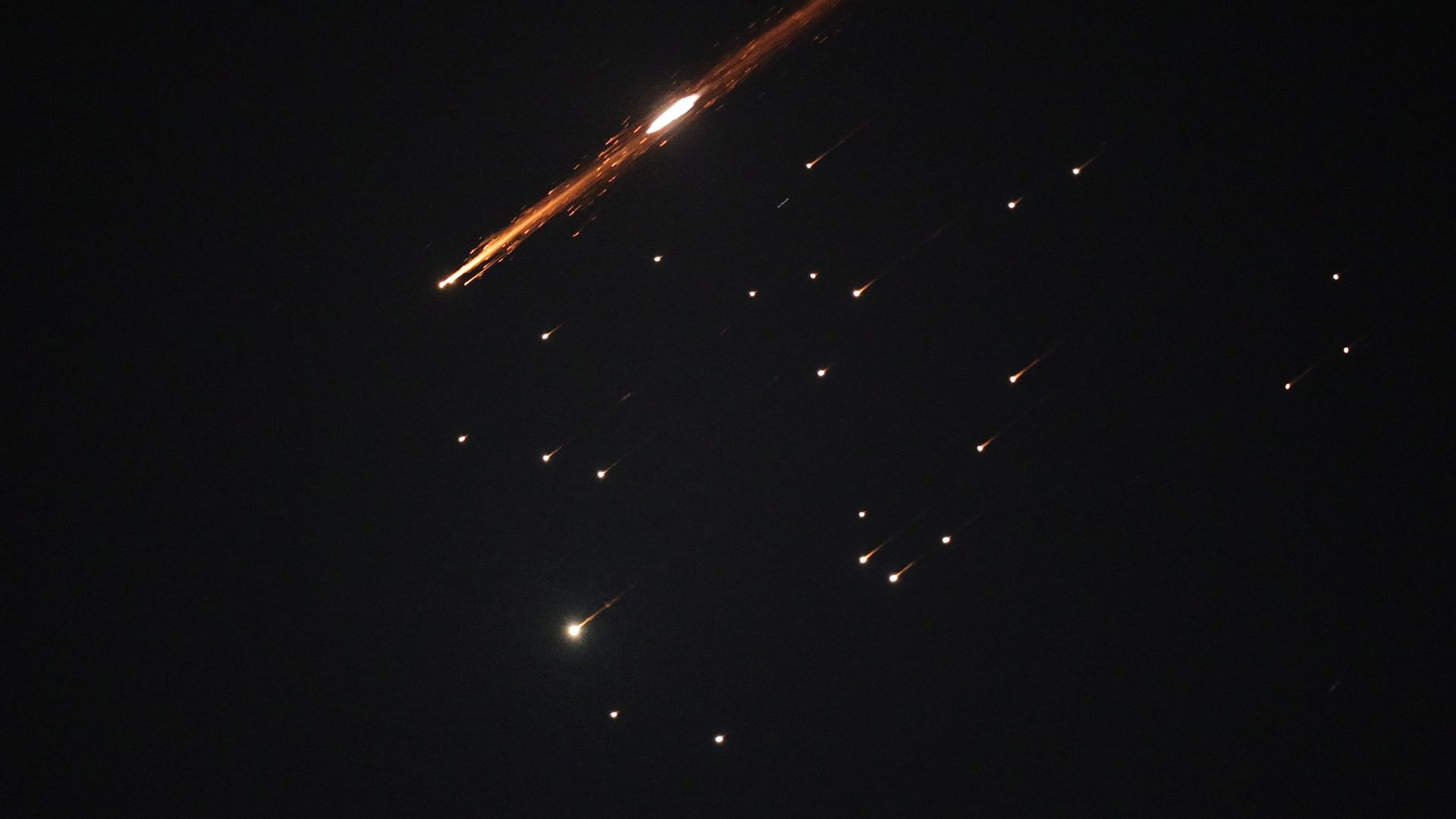 A night sky, streaked with red-orange missile salvos.