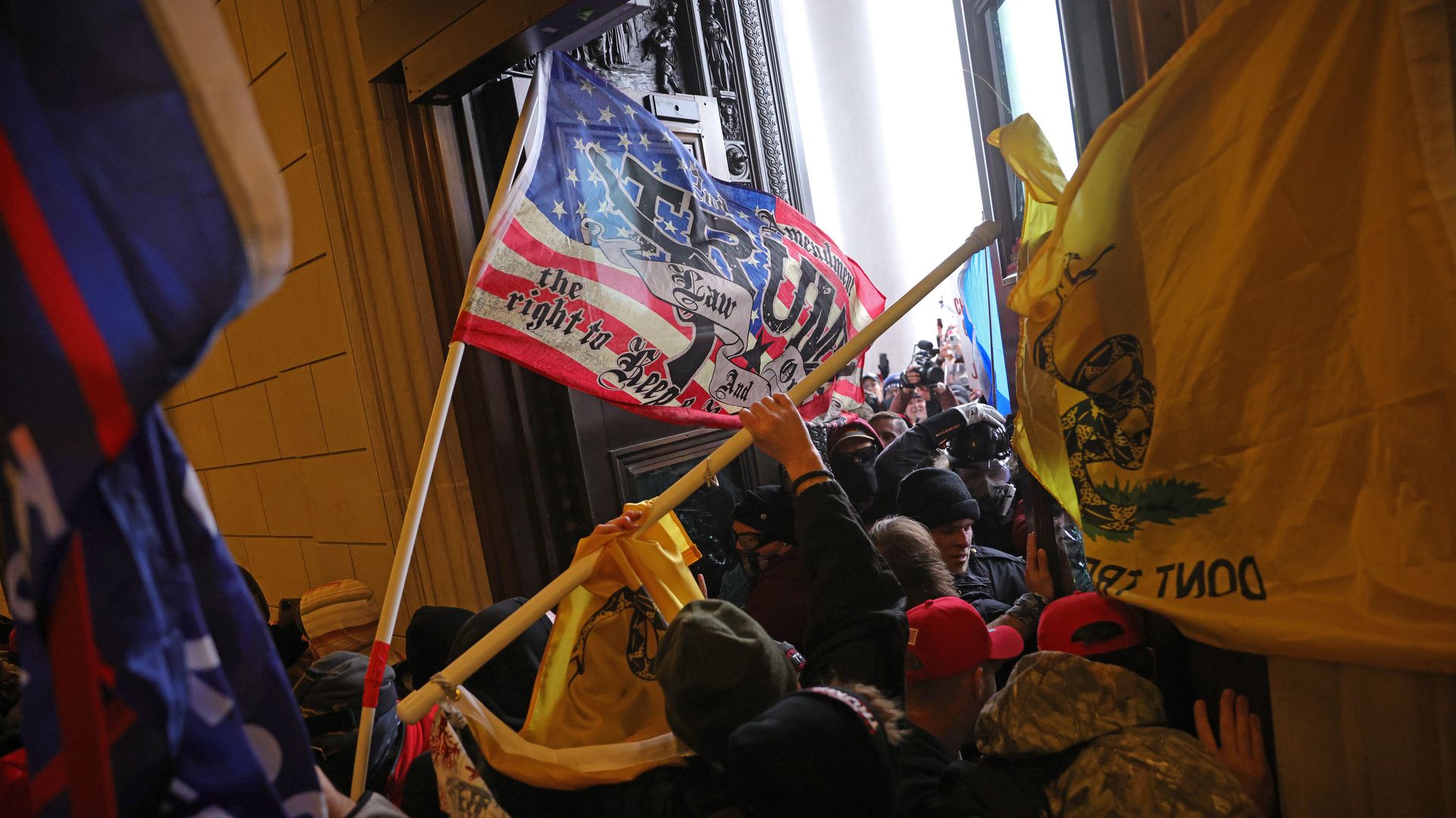 Photo of Trump supporters storming into the U.S. Capitol holding signs and flags