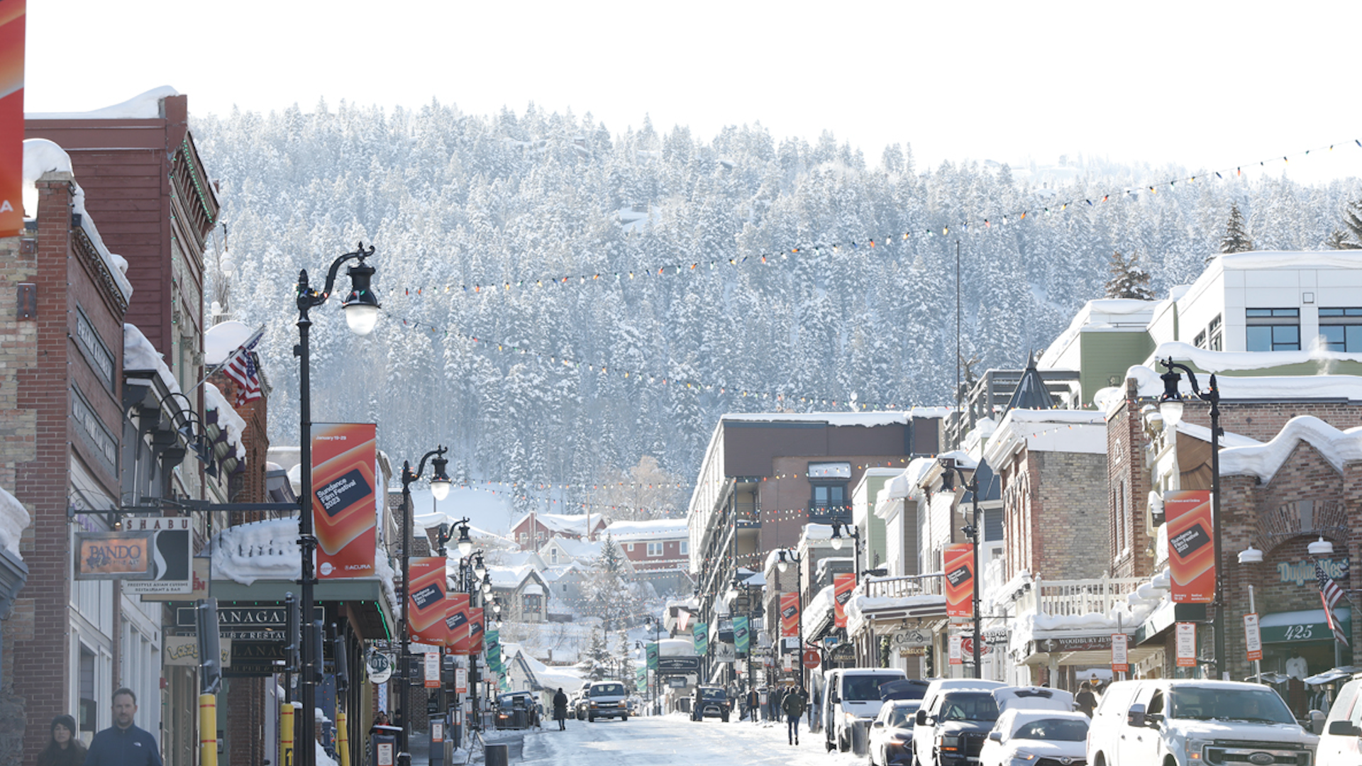 Park City's Main Street featuring signage of the Sundance Film Festival and snowy trees.