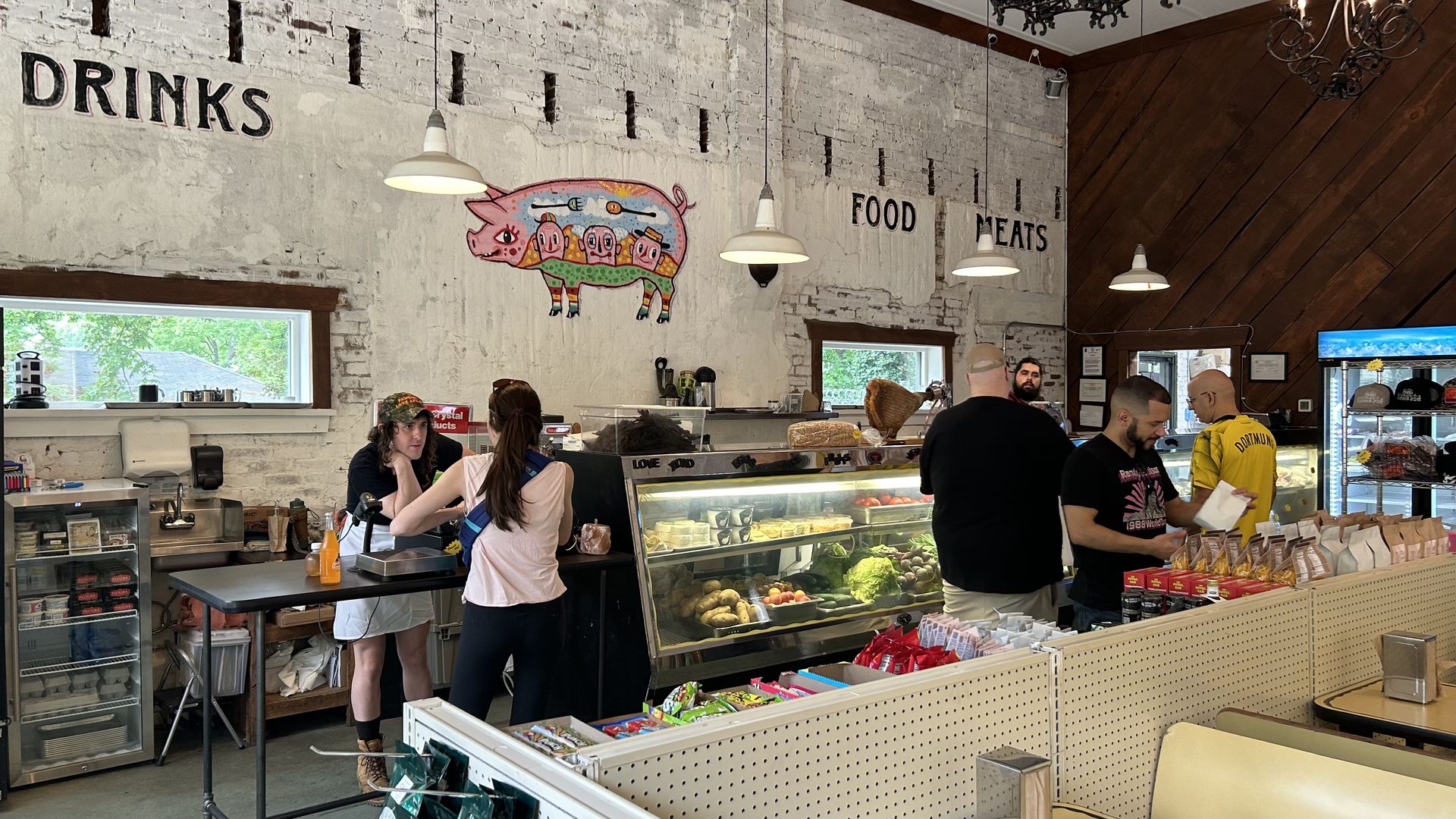 A superette and lunch counter restaurant with a large white wall that has a pig mural